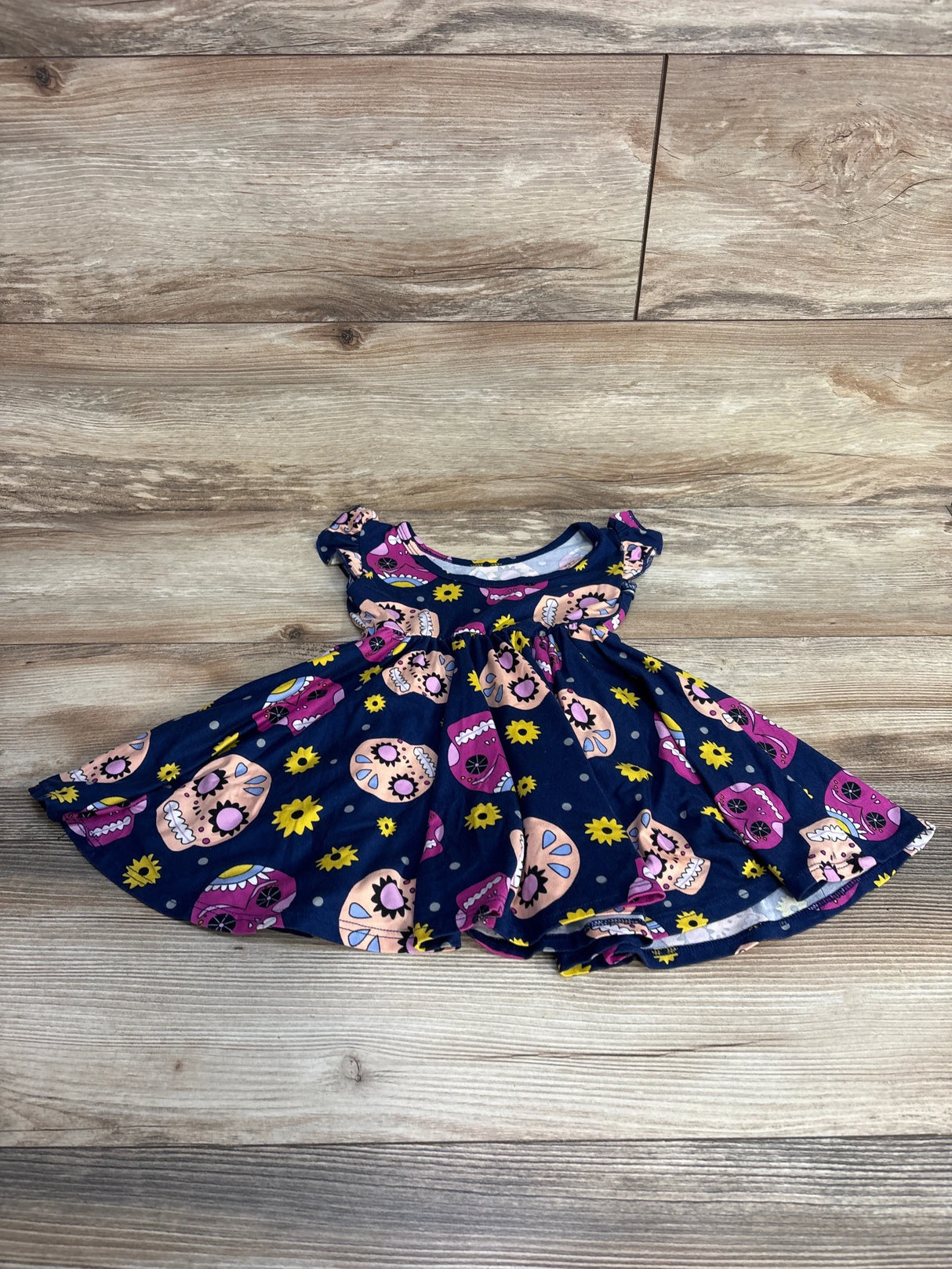 Navy blue doll dress with colorful sugar skull and yellow flower print on wood background