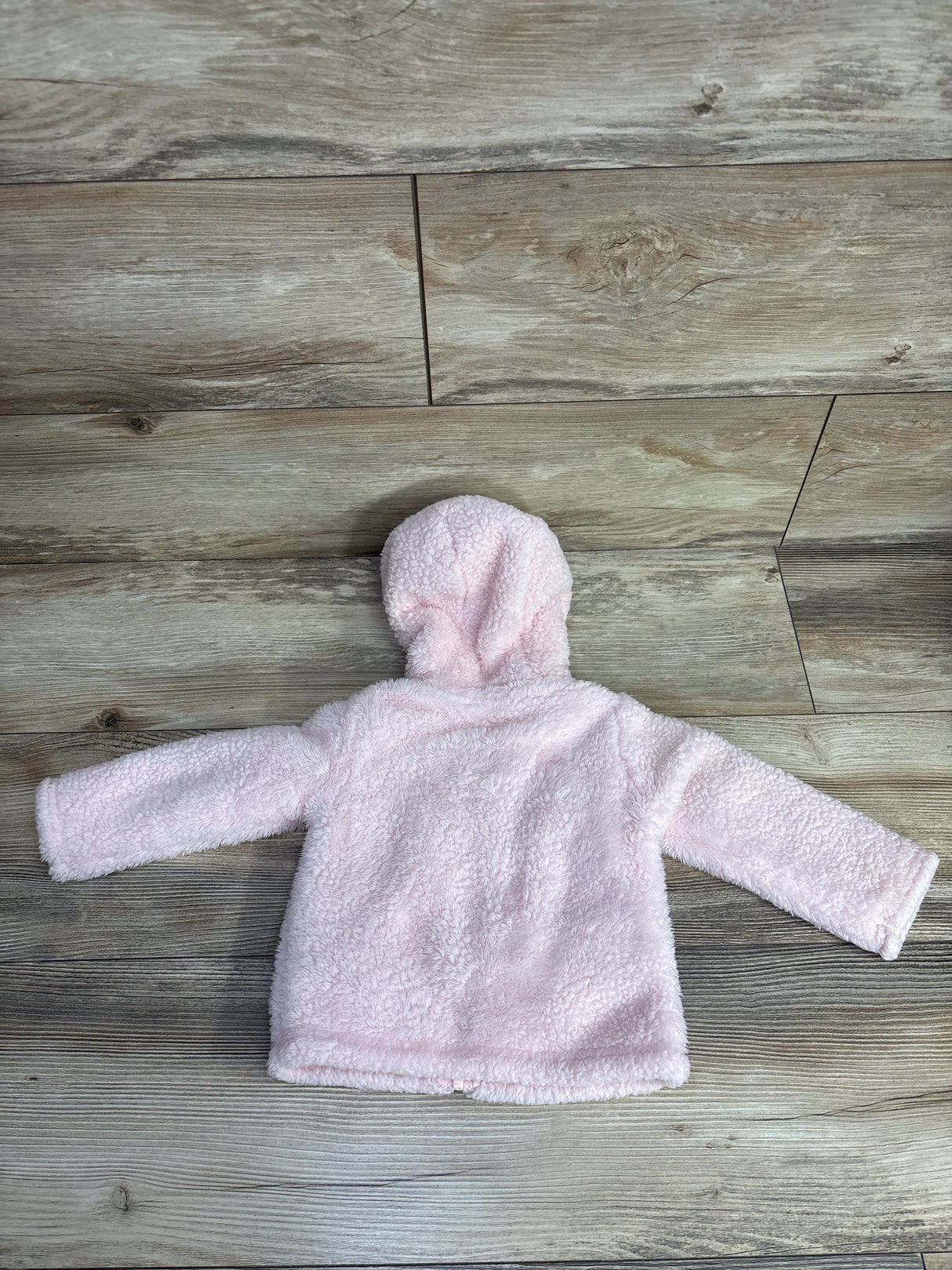 Soft pink toddler hoodie made of fluffy sherpa fleece on wood floor