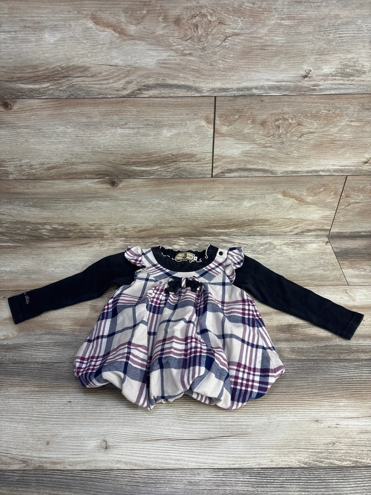 Flat lay of girls Classic Teddy plaid dress (2T) with navy long sleeves and pink navy white plaid skirt on wood
