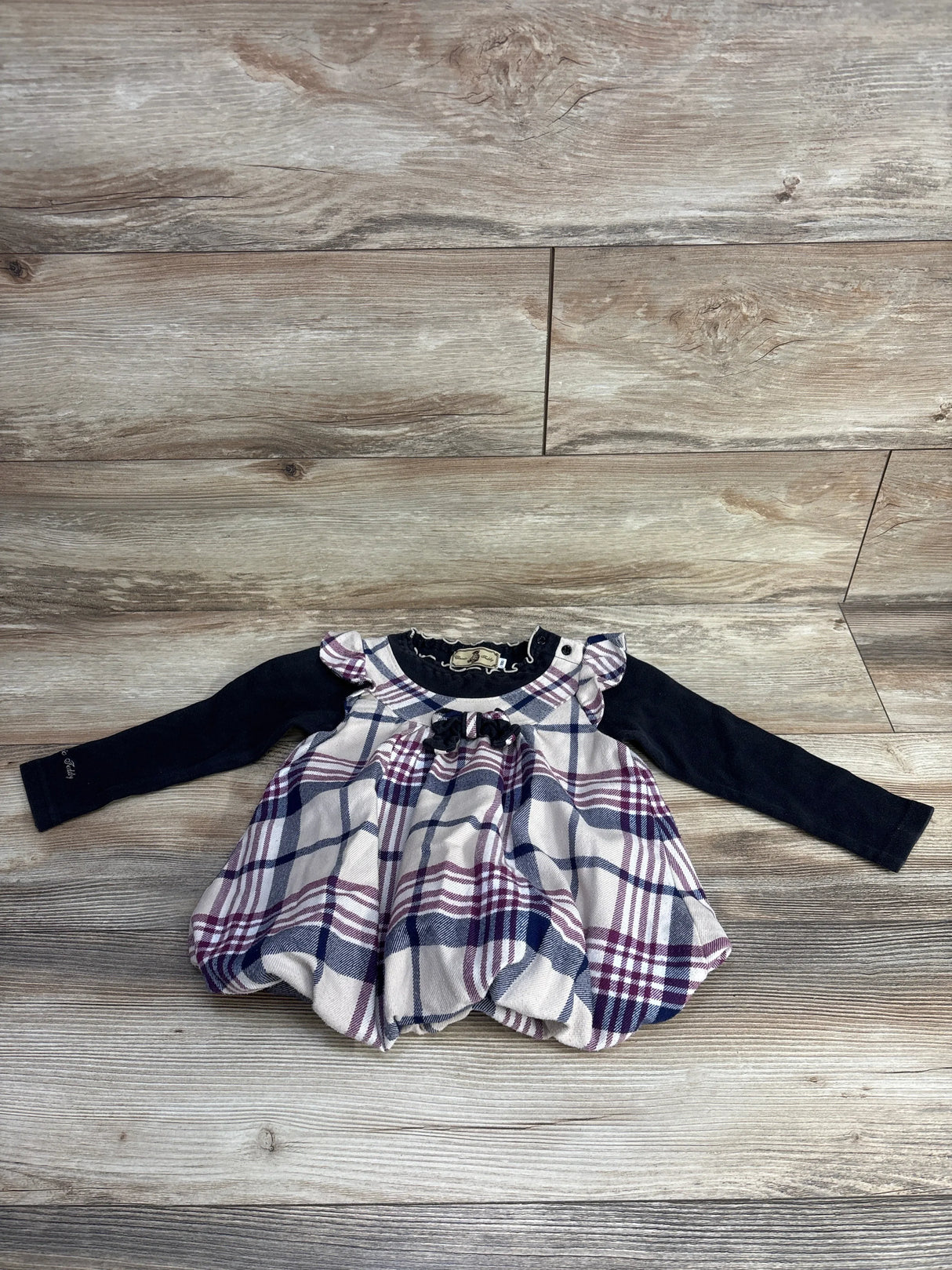 Flat lay of girls Classic Teddy plaid dress (2T) with navy long sleeves and pink navy white plaid skirt on wood