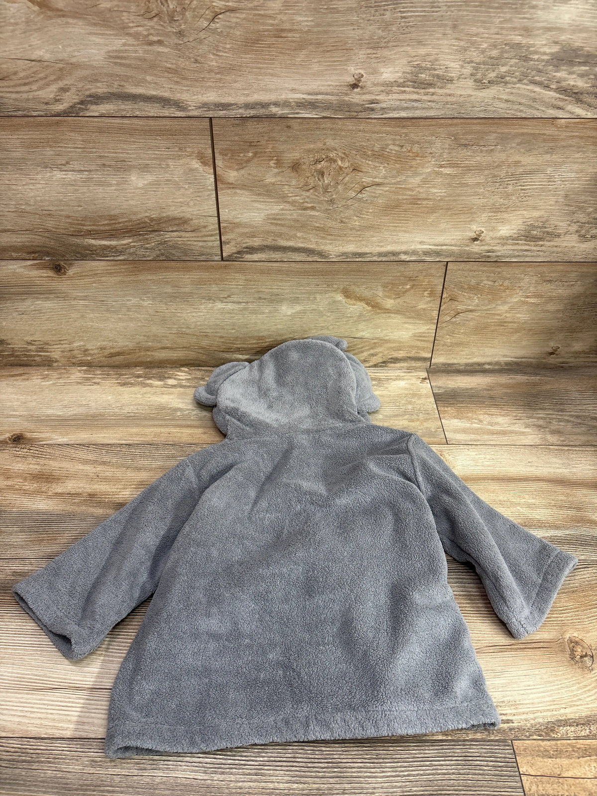 Back view of the gray hooded elephant bath robe showcasing its elephant-ear hood and long sleeves on a wood floor