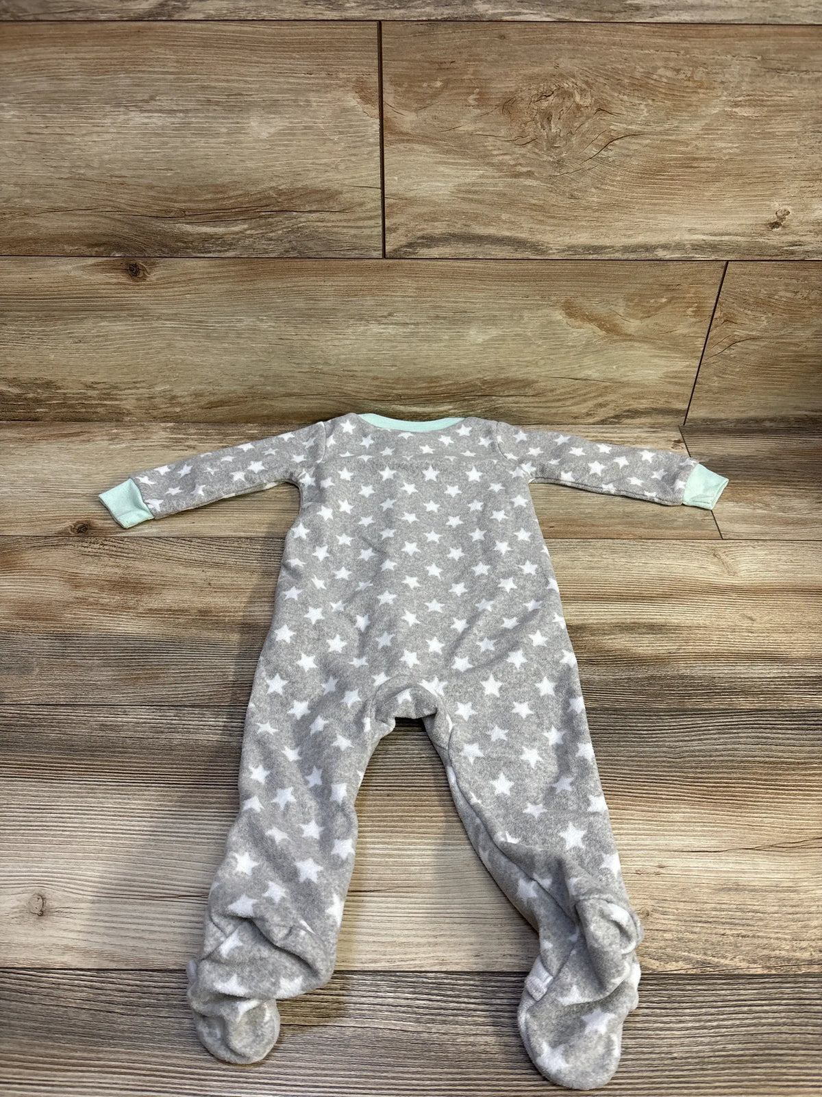 Flat lay of Simple Joys blanket sleeper, grey with white stars and mint trim, footed, size 6-9 months on wood background