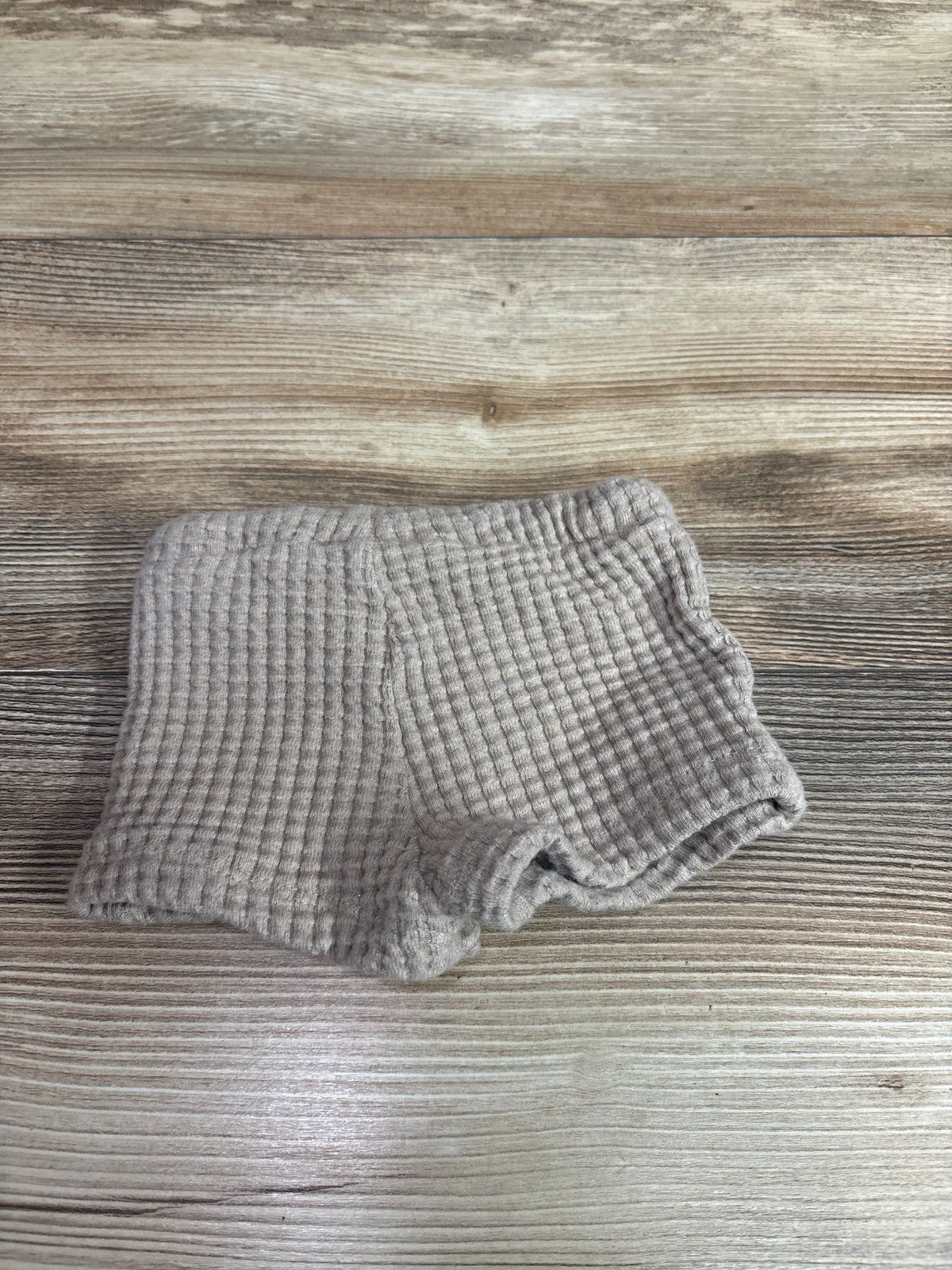 Beige knit drawstring preemie shorts on a wooden surface