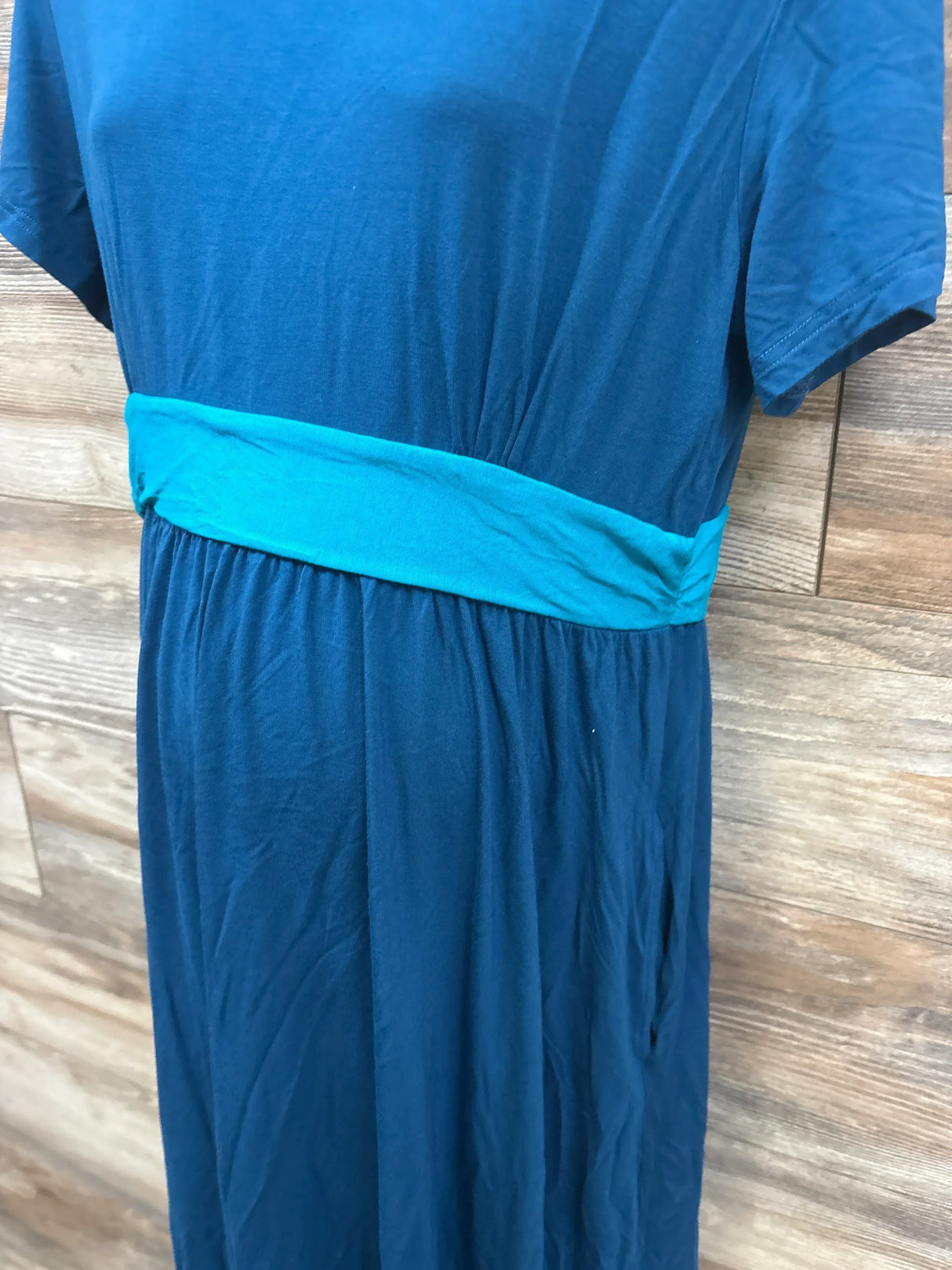 Blue short sleeve maternity dress with light blue waist band against wood background