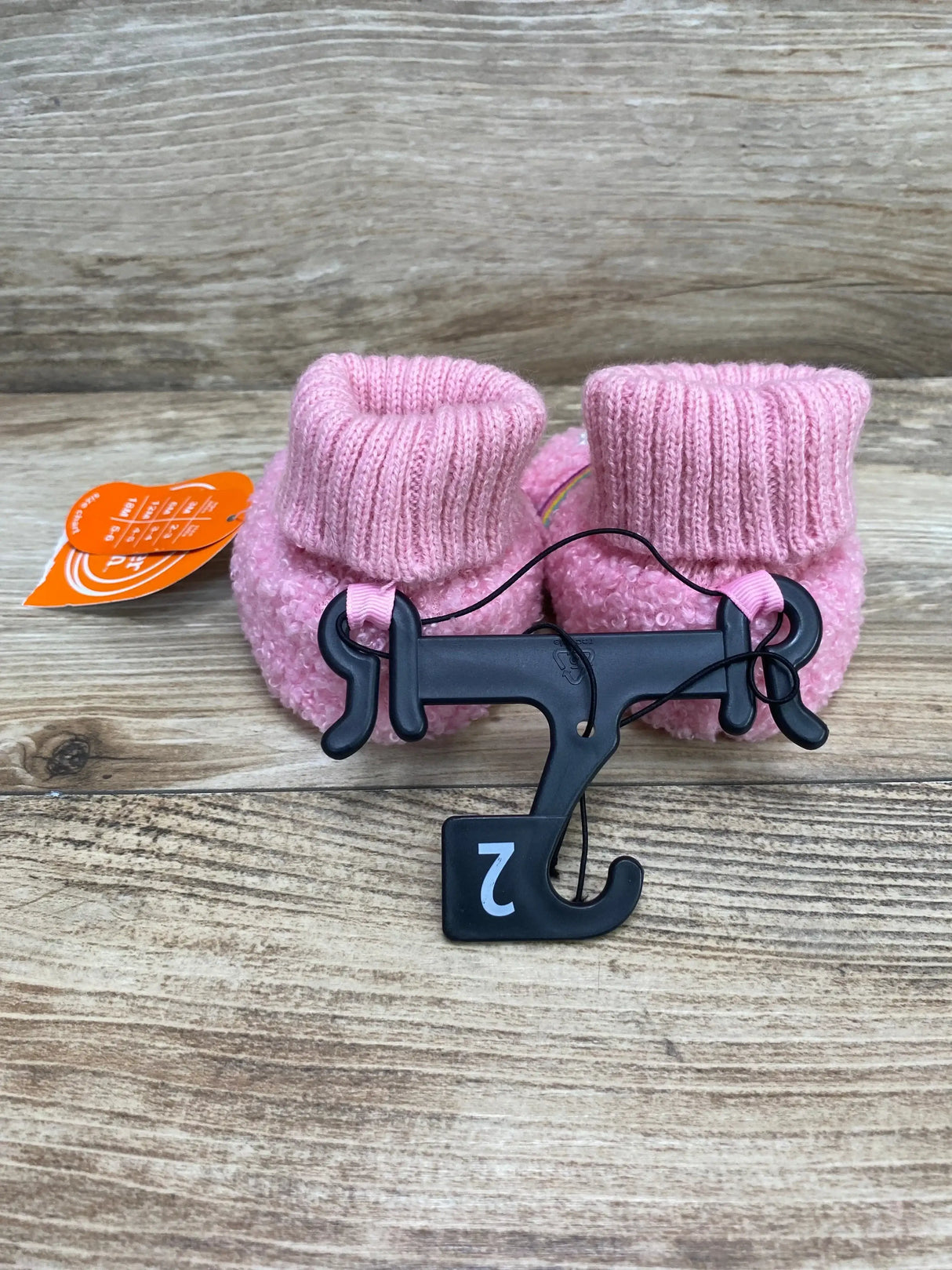 Front view of pink Wonder Nation baby bootie slippers (size 2C) showing ribbed knit cuffs and fuzzy textured body on wooden tabletop