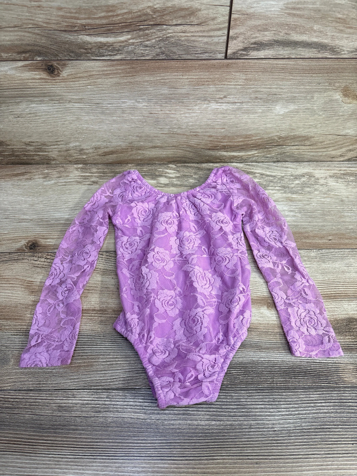 Purple lace long sleeve baby bodysuit on wood background