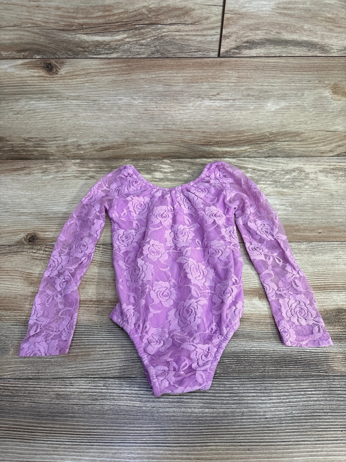 Purple lace long sleeve baby bodysuit on wood background