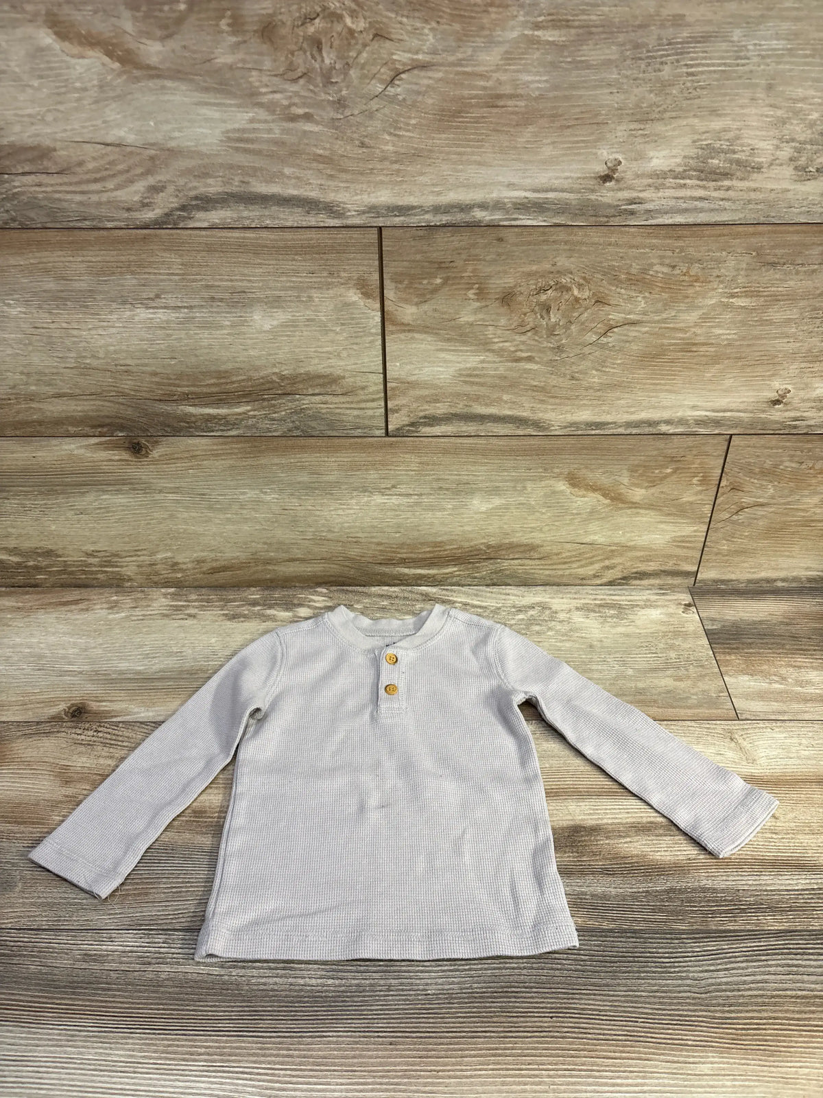 Front view of Jumping Beans grey waffle knit Henley shirt, size 18 months, with buttoned placket and long sleeves on wood