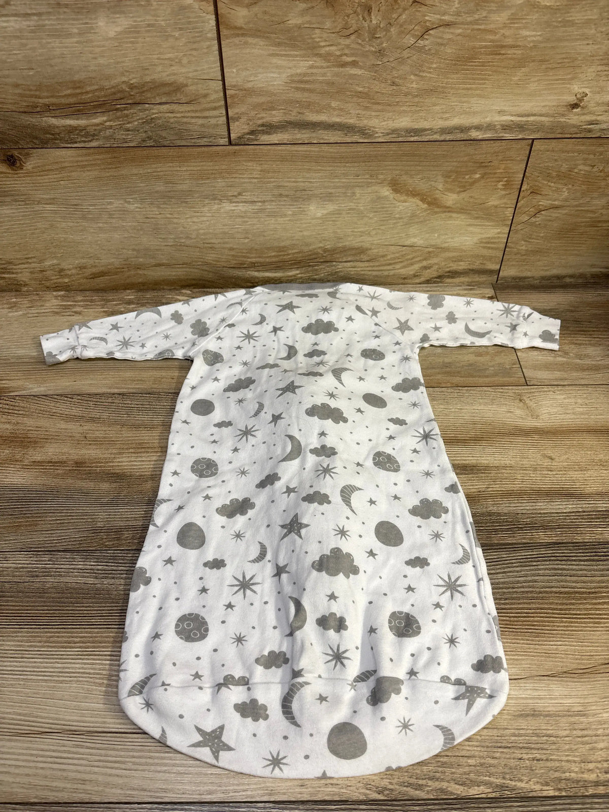 Flat lay of Spasilk sleep bag showing long sleeves and gray moon, star and cloud print on a wood surface