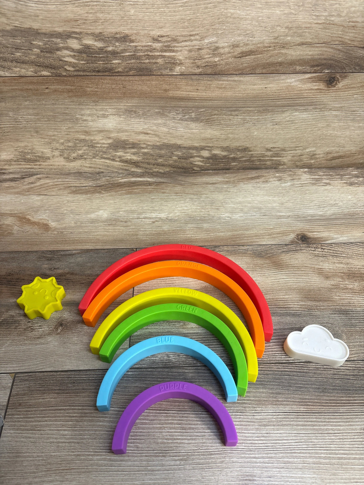 Colorful rainbow stacking toy with sun and cloud on wood background