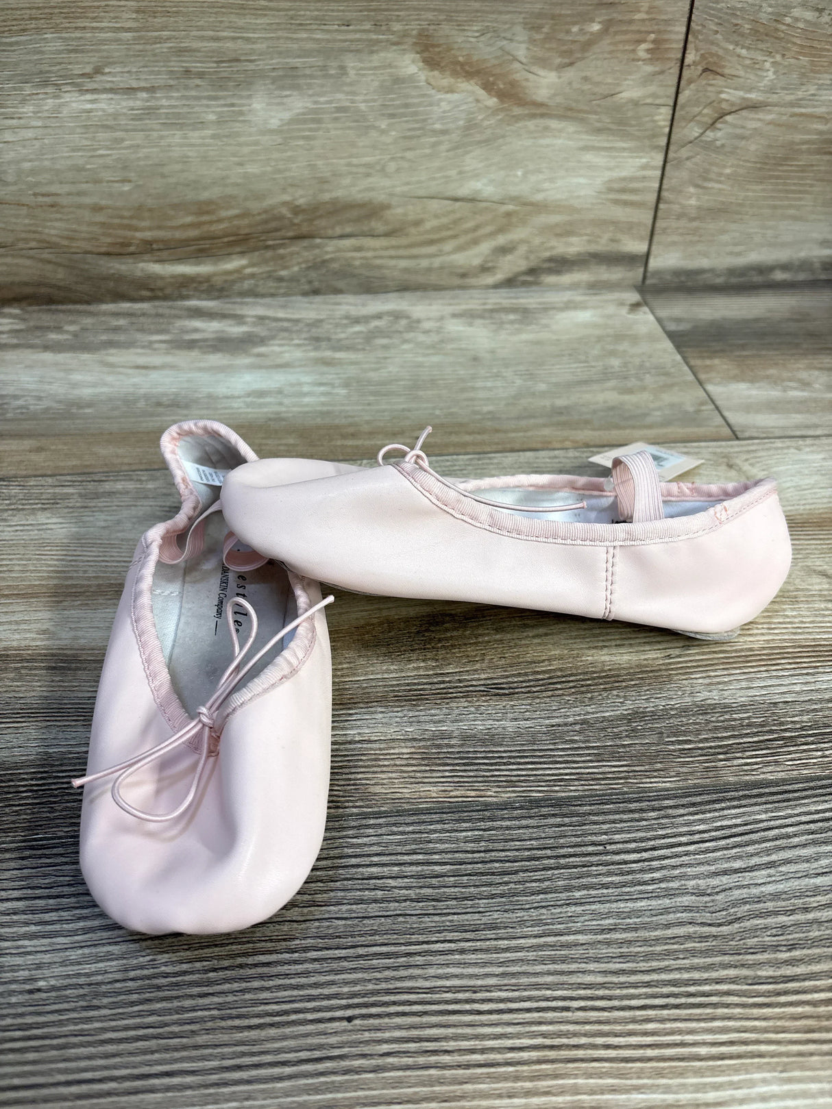 Light pink ballet slippers with bows on wooden floor