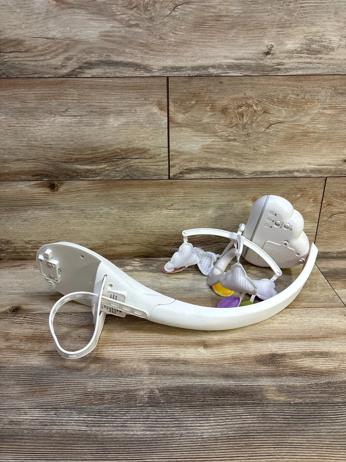 Angled view of Fisher-Price Calming Clouds Crib Mobile and Soother with plush clouds and colorful raindrops on a wooden surface
