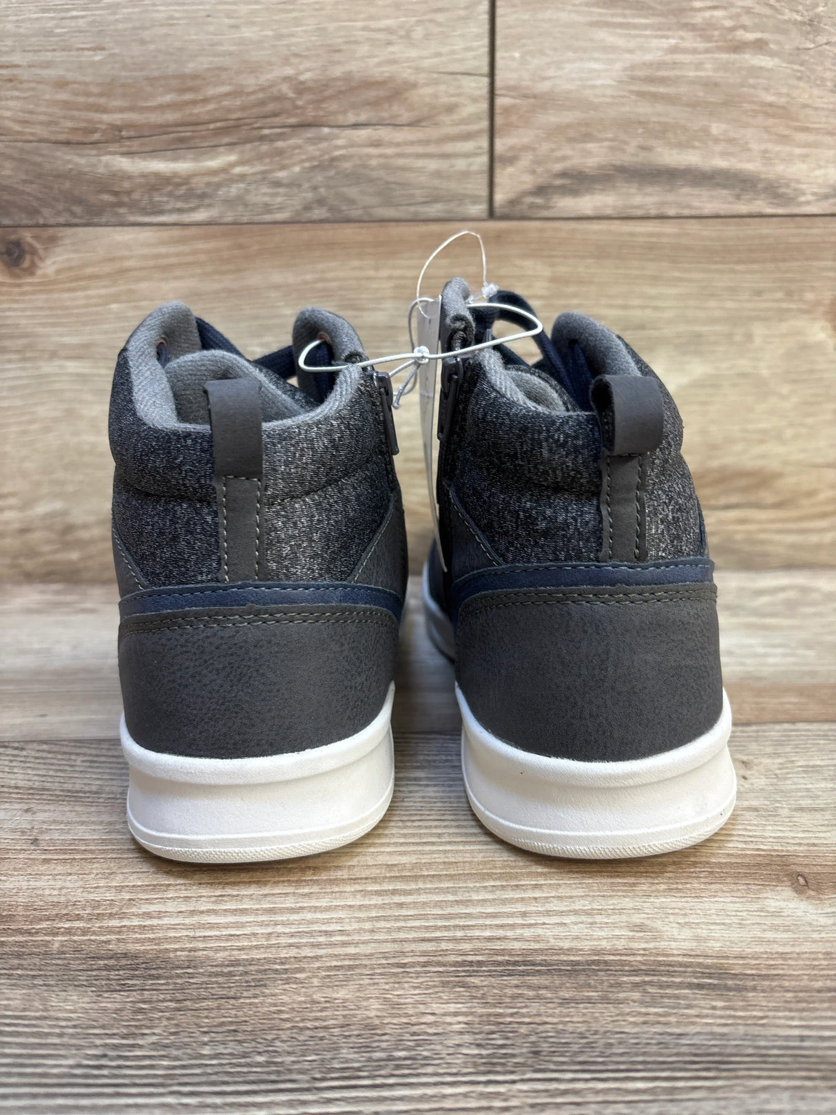 Back view of kids' dark grey high-top sneakers with white soles on wood floor