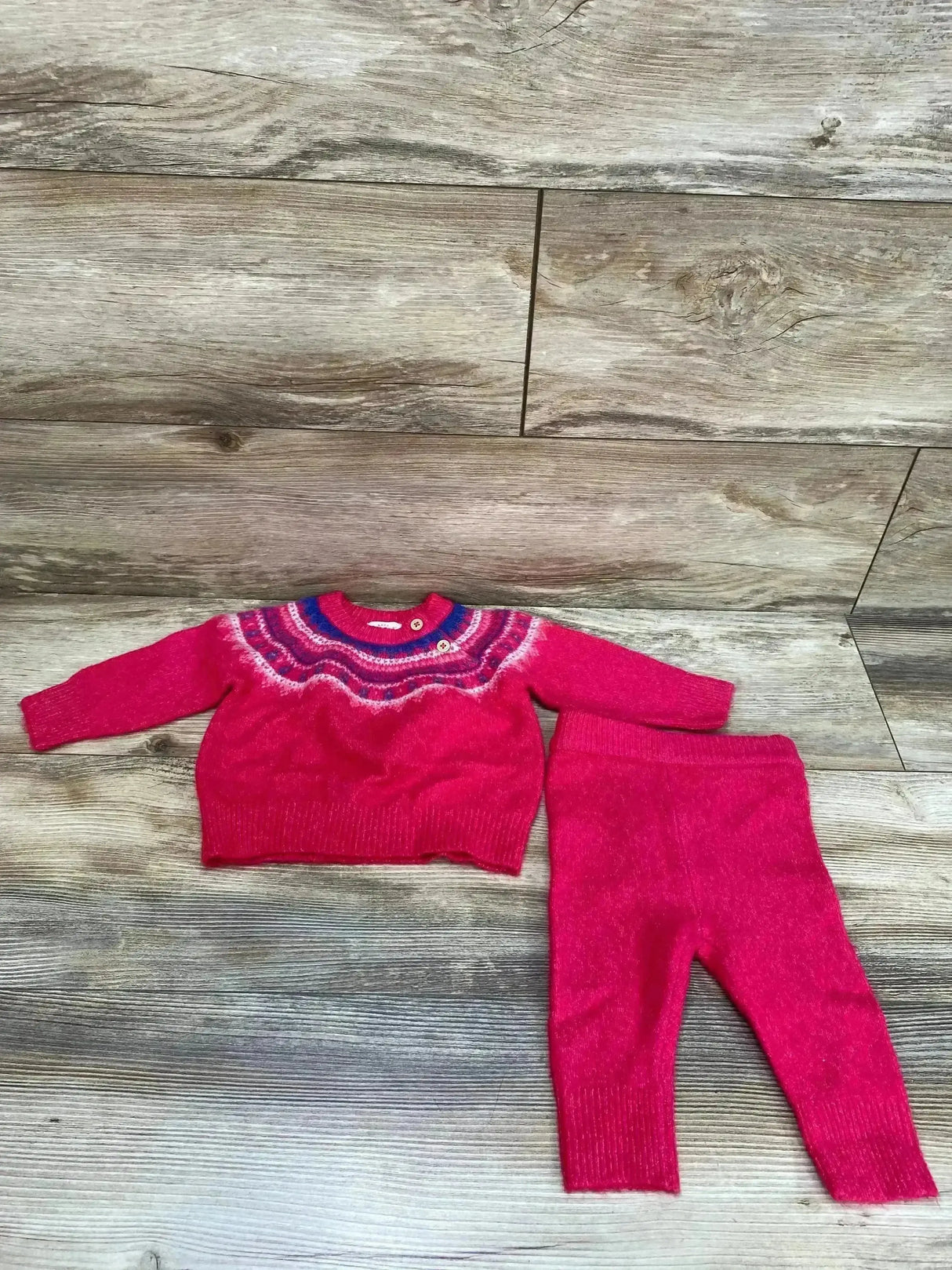 Top-down of Cat & Jack pink Fair Isle sweater and pants showing patterned yoke, buttons, ribbed trim on wood background