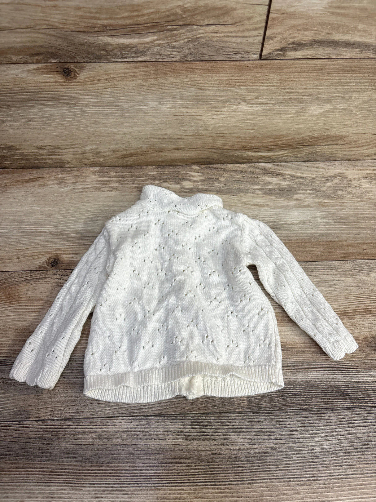 White knit toddler sweater with long sleeves on wooden background
