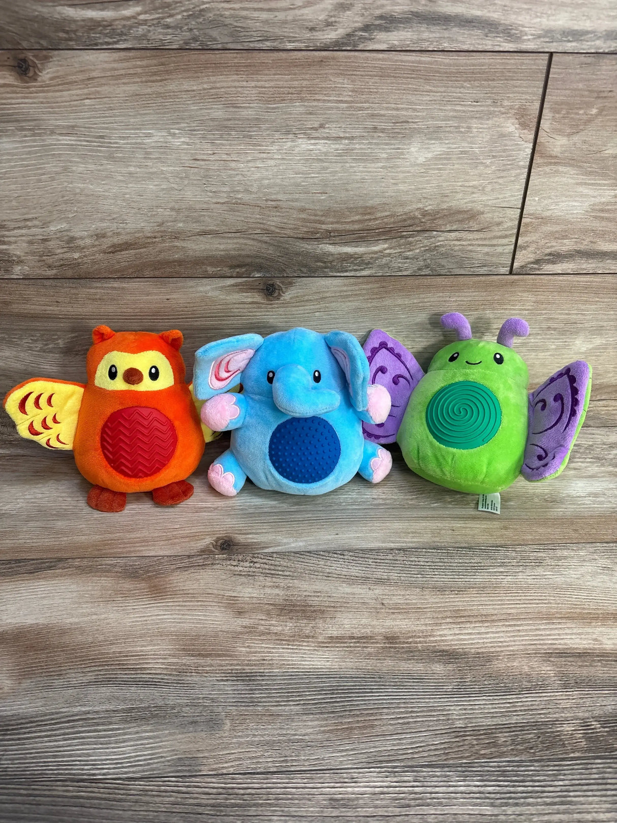 Front view of Lakeshore Sensory Friends set (owl, elephant, butterfly) showing textured belly pads on wood background