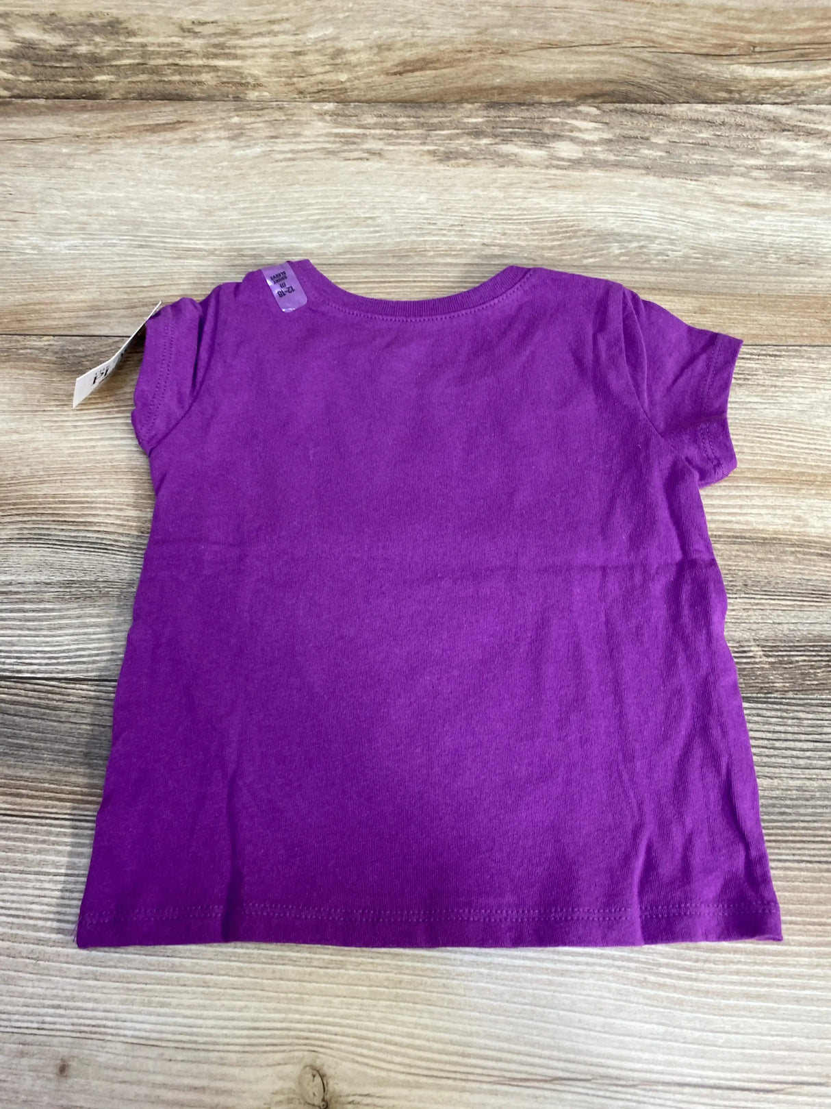 Back view flat lay of Children’s Place Hallo Queen purple toddler T-shirt showcasing short sleeves and visible size tag on wood background