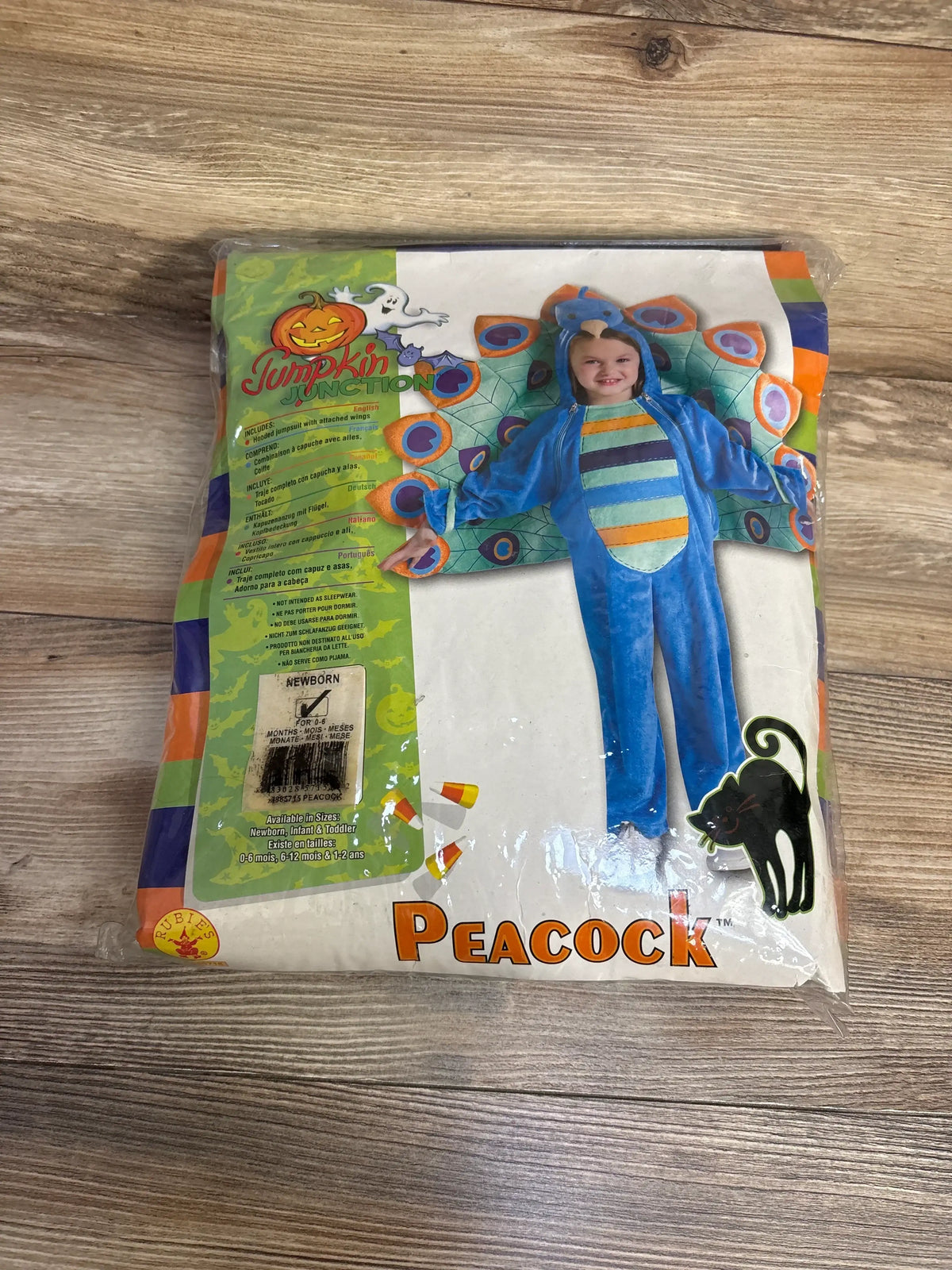 Front view of Rubies Peacock costume package showcasing blue peacock design and newborn 0 to 6 month size on wood background