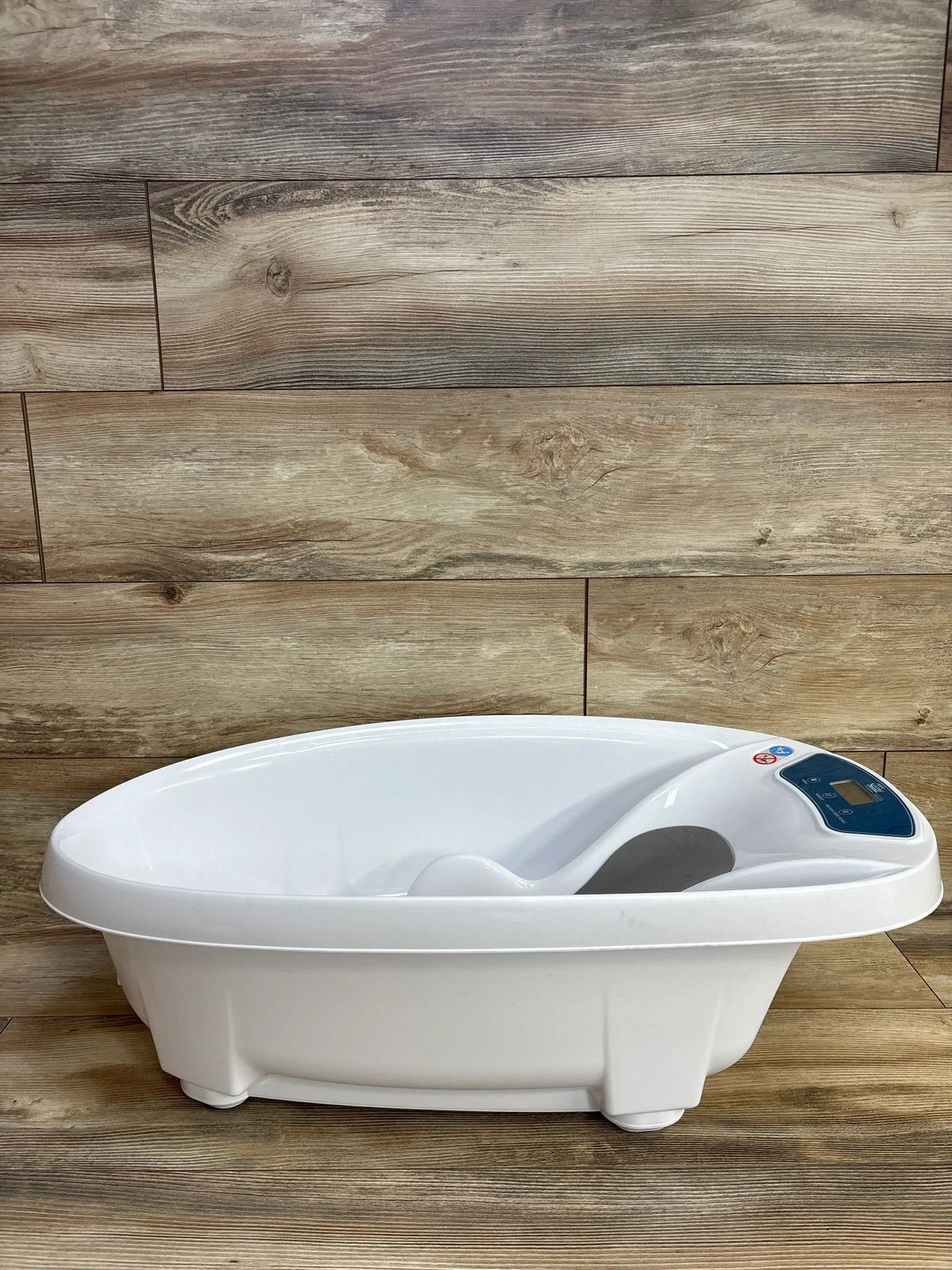 white digital baby bathtub with ergonomic contoured seat on wooden floor background