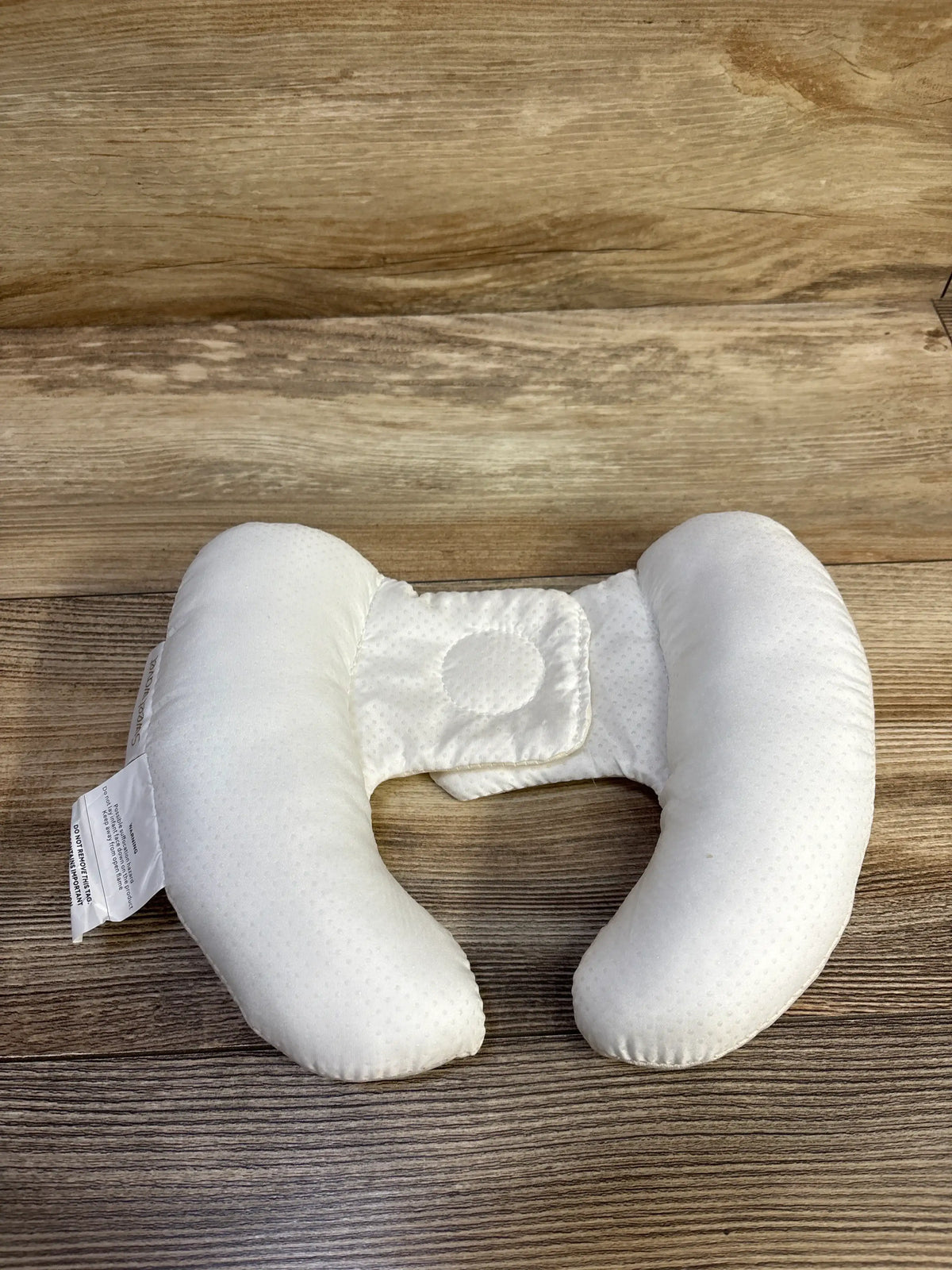 Front view of Sweetwavet cream car seat and stroller neck pillow with U-shaped cushioning and center strap on wood surface