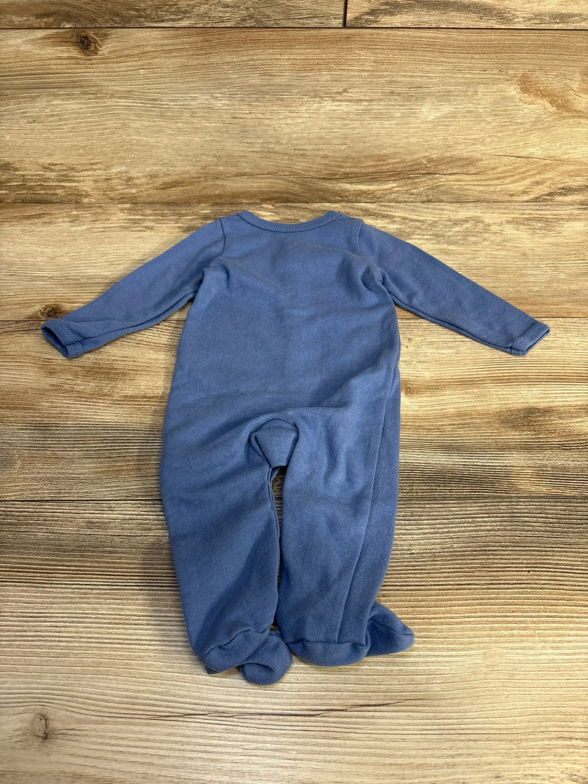 Back view of blue Sterling Baby Penguin footed sleeper with long sleeves and built-in feet on wood background