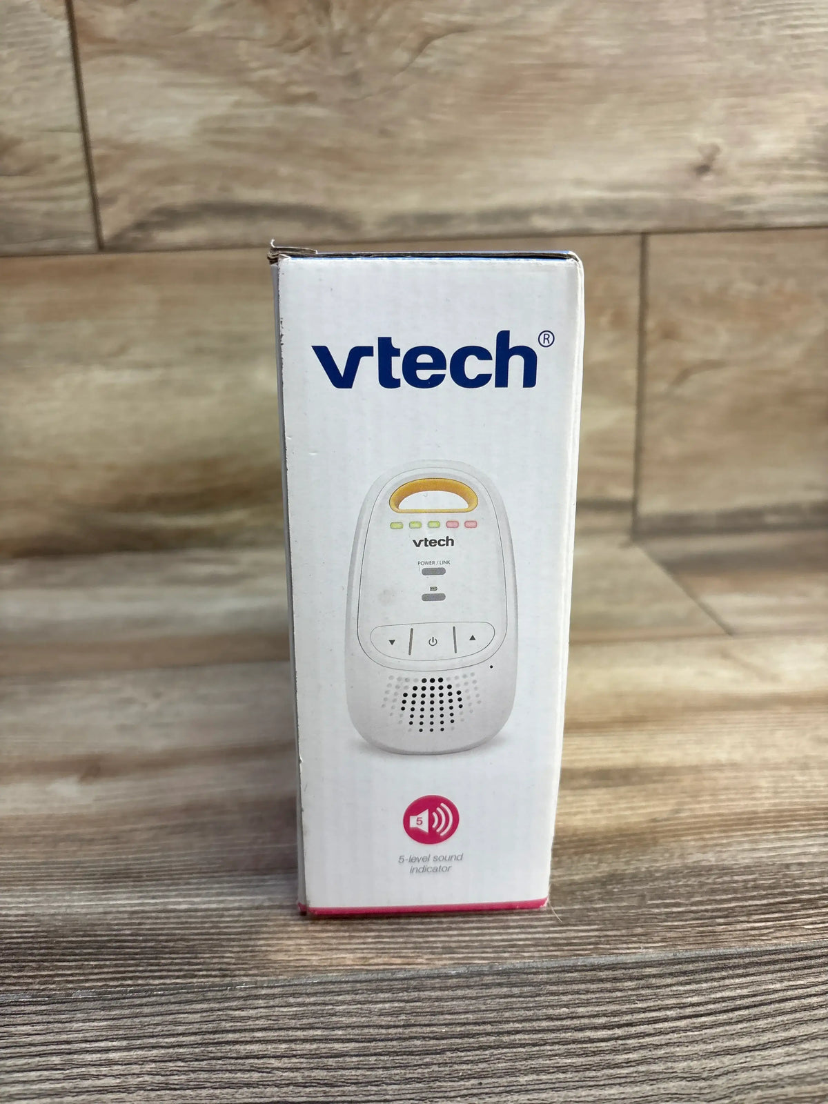 Front of VTech DM111 monitor box showing VTech logo and unit image with five-level sound indicator on wood