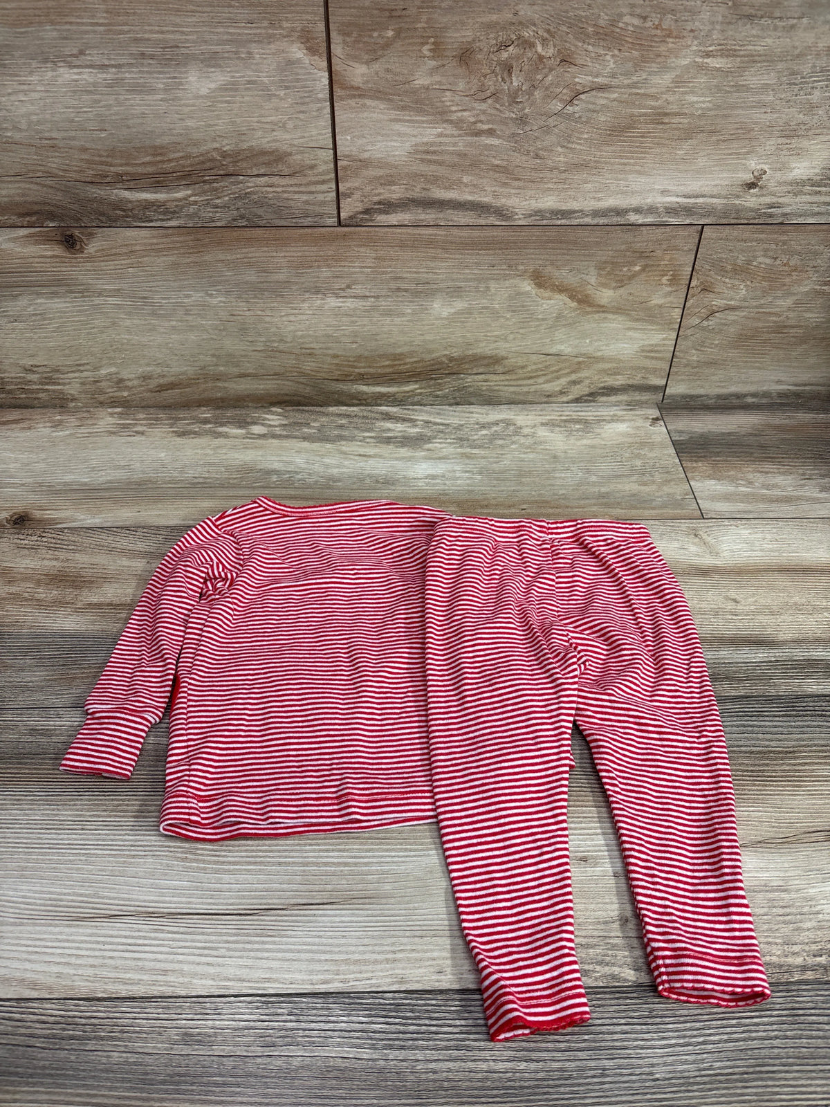 Carter's 2-piece red and white striped pajama set for infants on a wood background.