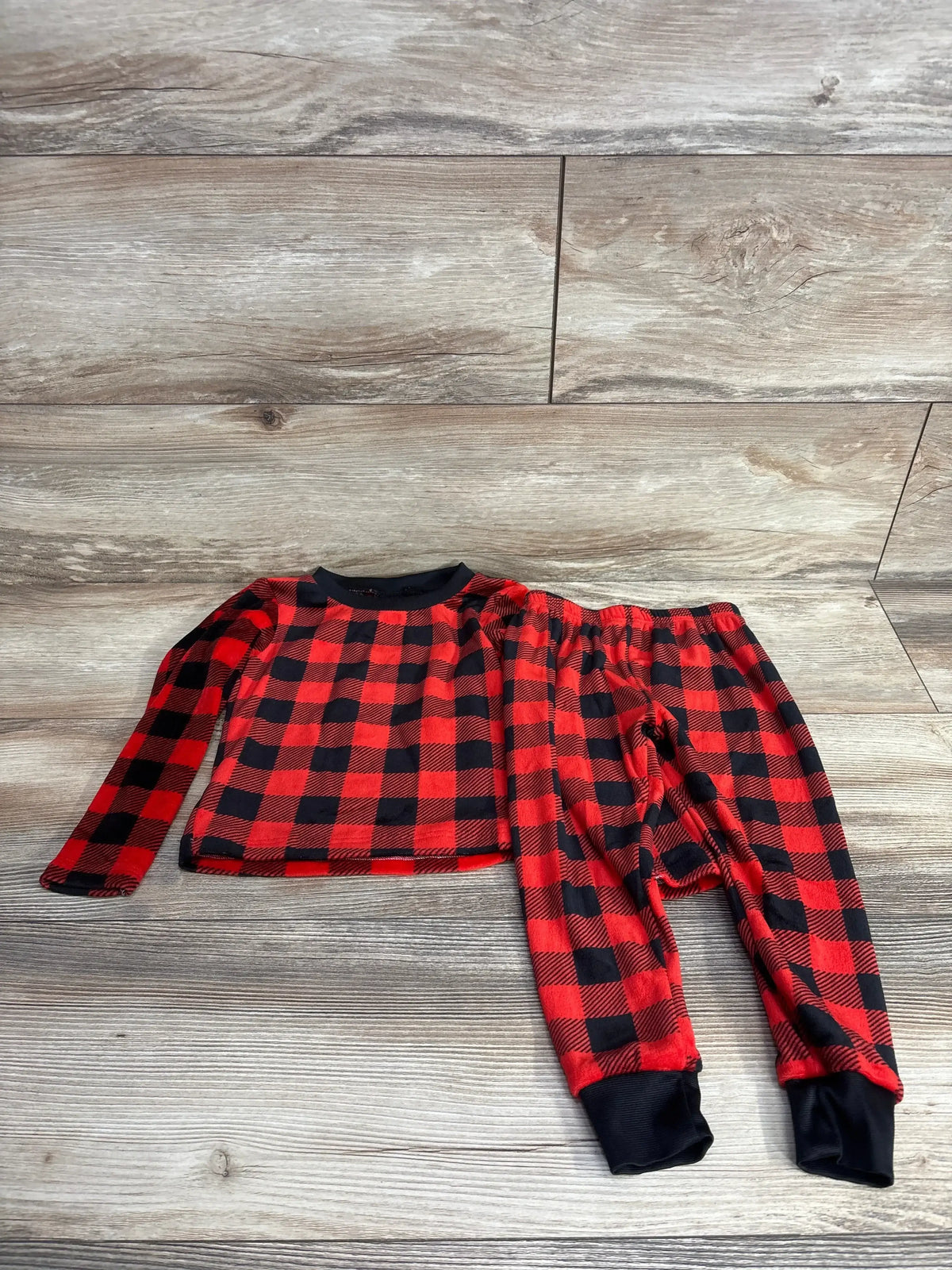 Red and black plaid long sleeve toddler pajama set with black cuffs on wood floor