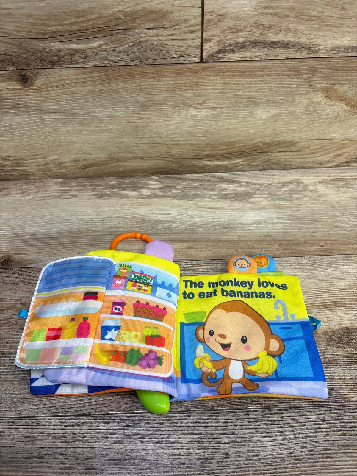 Opened VTech Peek & Play book showing peek-a-boo fridge flap, monkey illustration and text ‘The monkey loves to eat bananas’