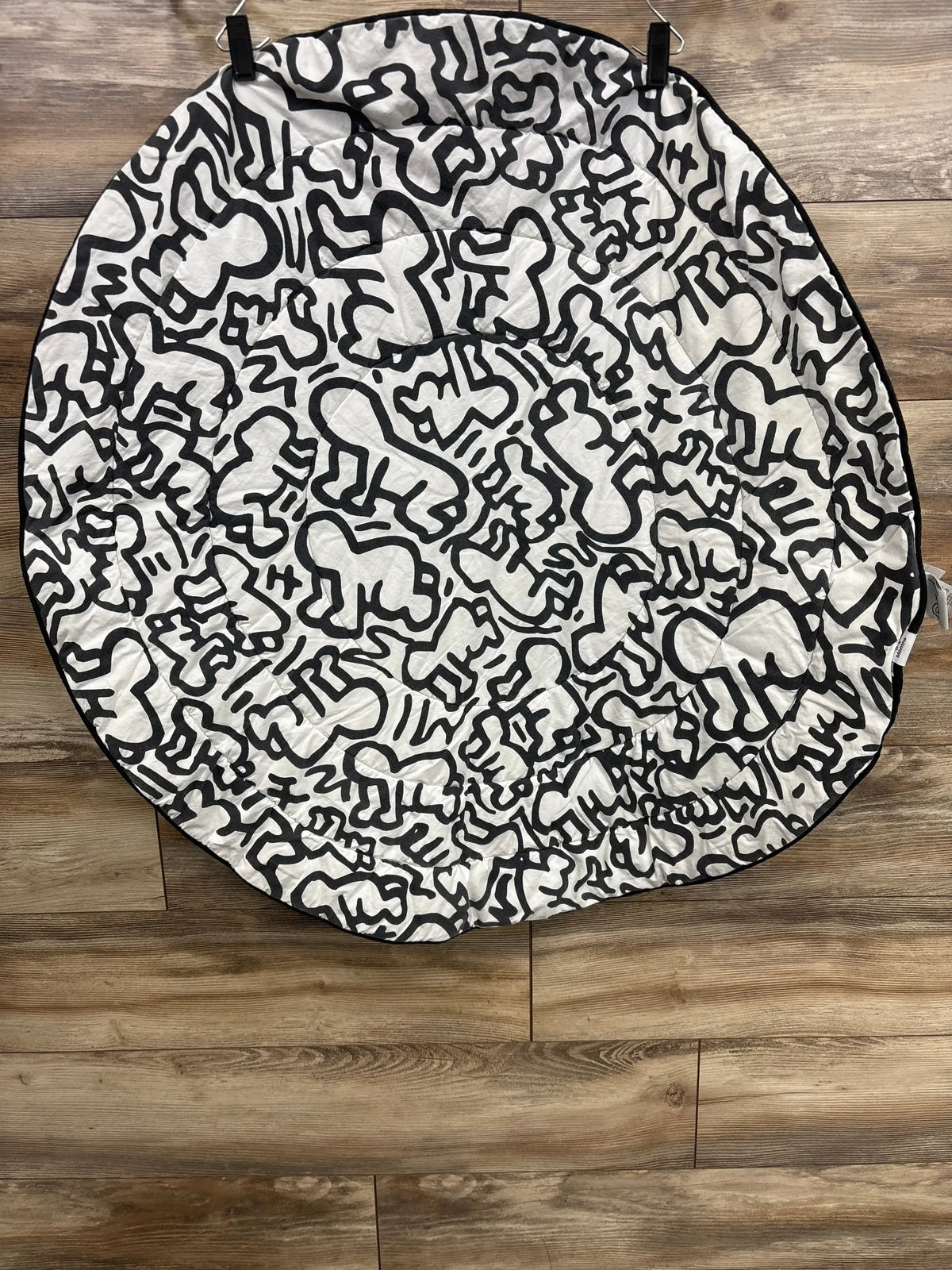 Top view of Etta Loves x Keith Haring reversible playmat showing black-and-white figures on wood floor