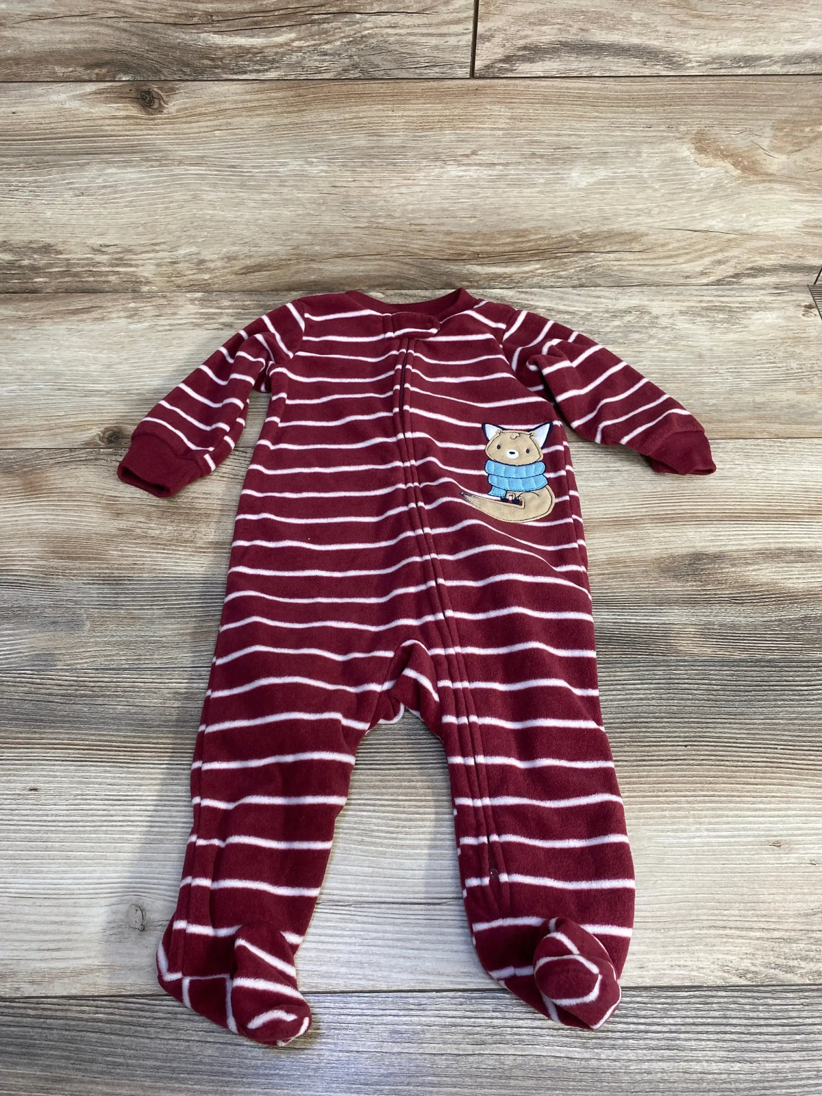 Flat lay of Carter’s red and white striped footed blanket sleeper showing front zipper and fox applique on wood floor