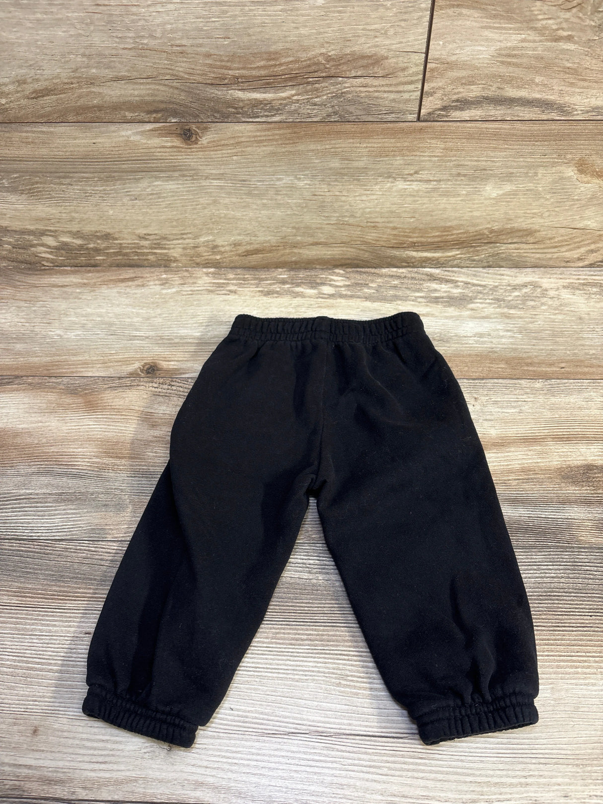 Flat lay of Baby Gap pull-on joggers size 12-18 months showcasing elastic waistband and gathered cuffs on wood floor background
