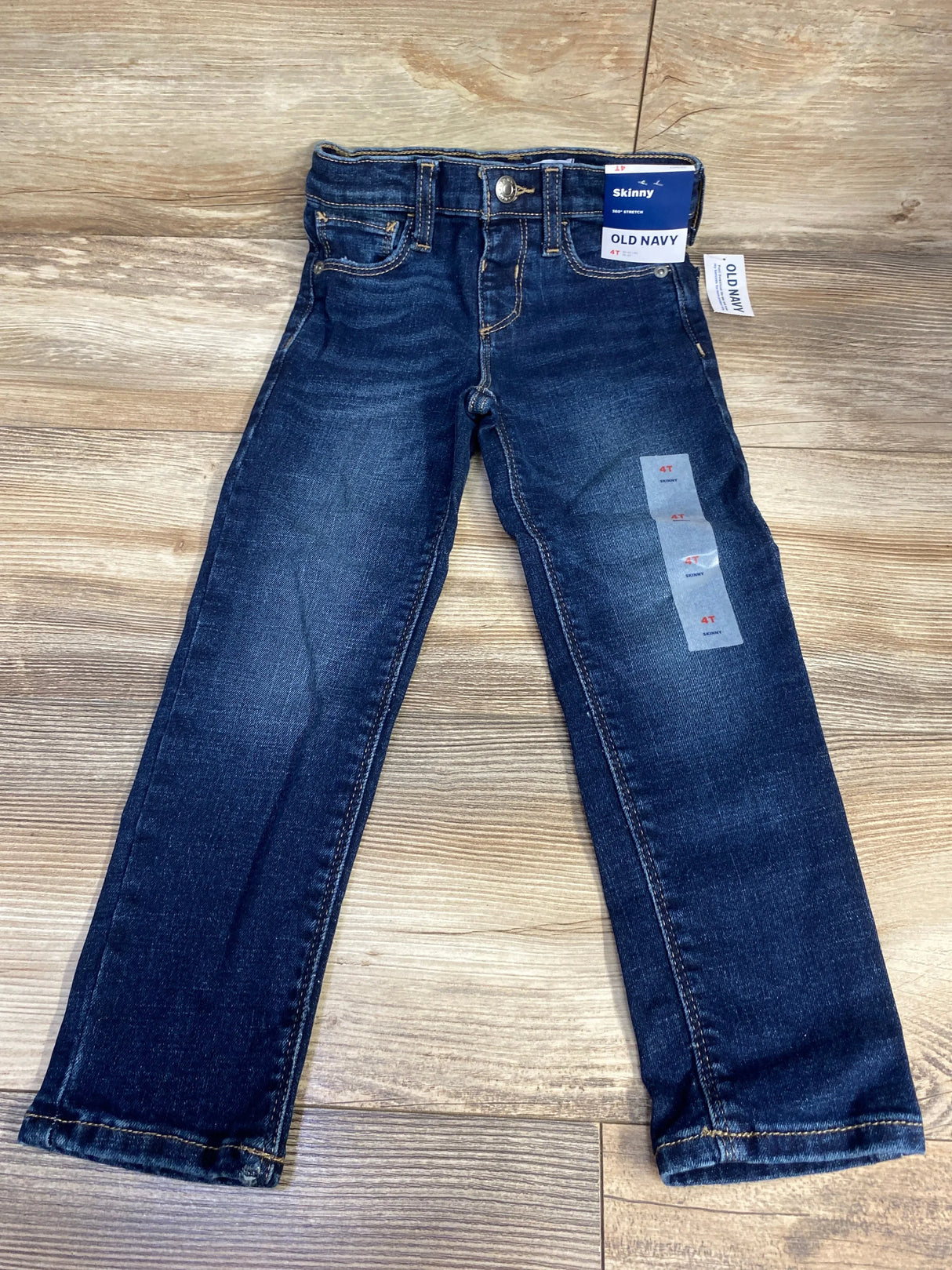 Kids dark wash skinny jeans, size 4T, with tags, laid flat on wood floor