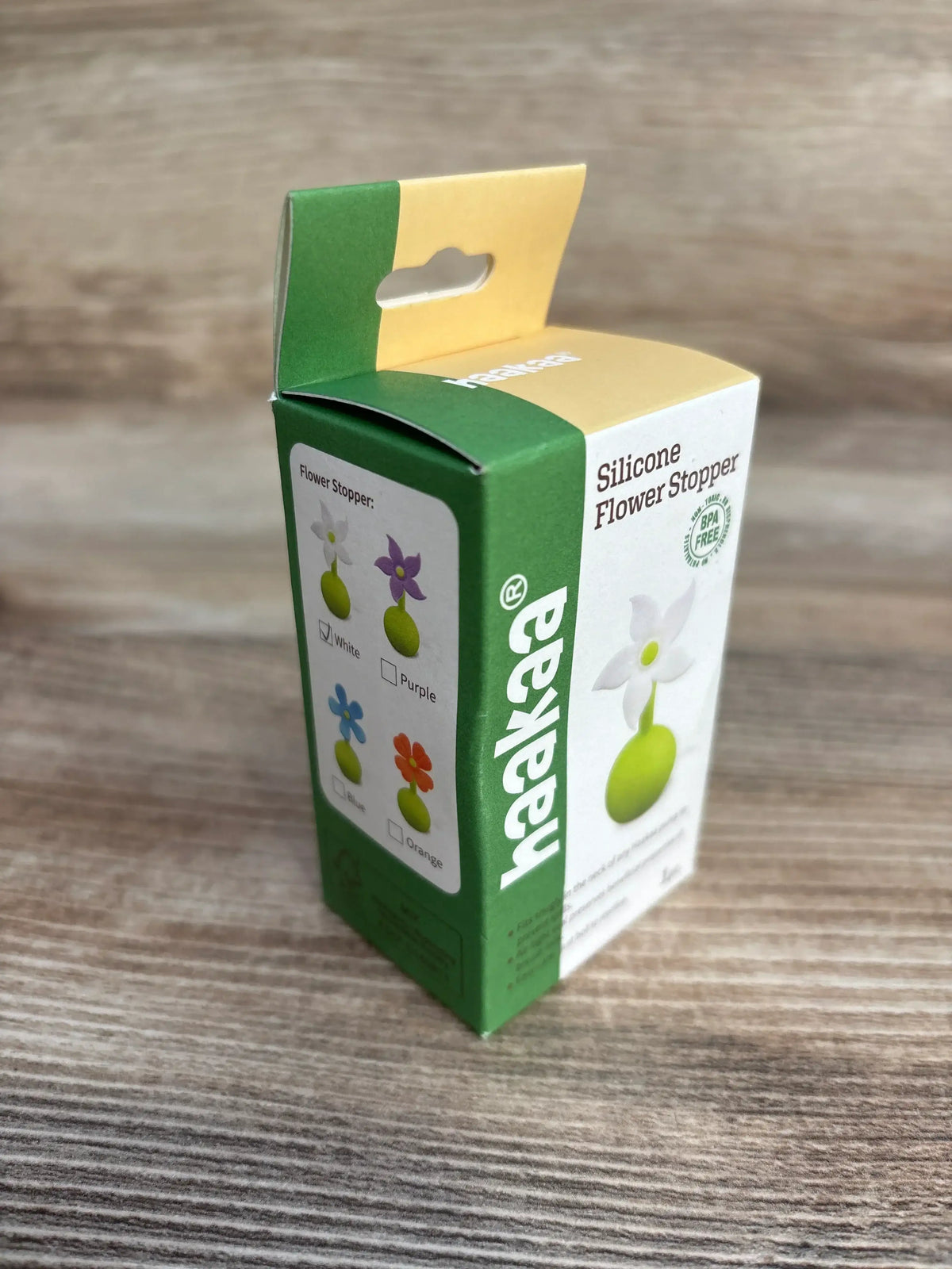 Three quarter view of Haakaa Silicone Flower Stopper box showing white flower and green base image with BPA free mark on wood