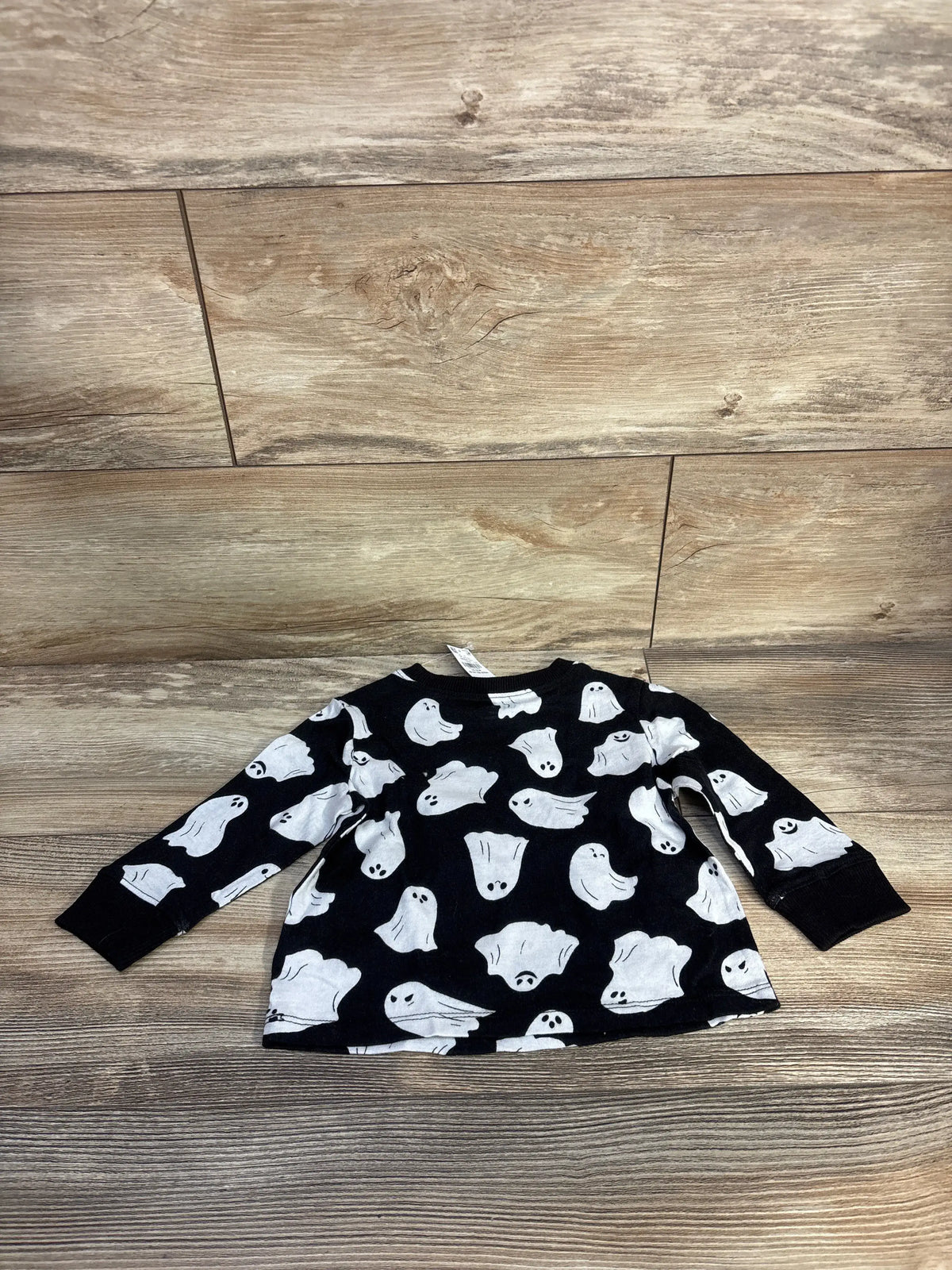 Front view of black Old Navy ghost shirt for ages 12-18 months showcasing long sleeves and white ghost print on a wood floor