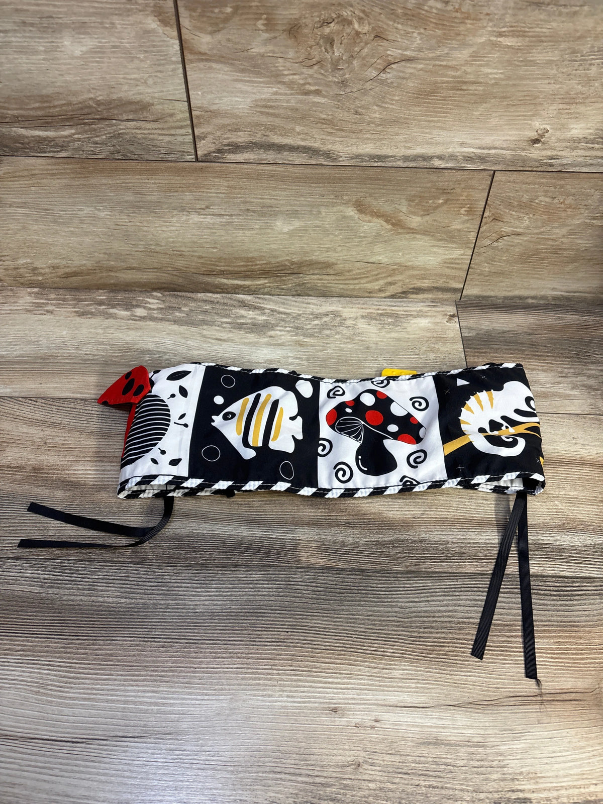 Front view of Baobrava High Contrast Tummy Time Book showcasing high contrast animal designs with fabric ties on a wood floor