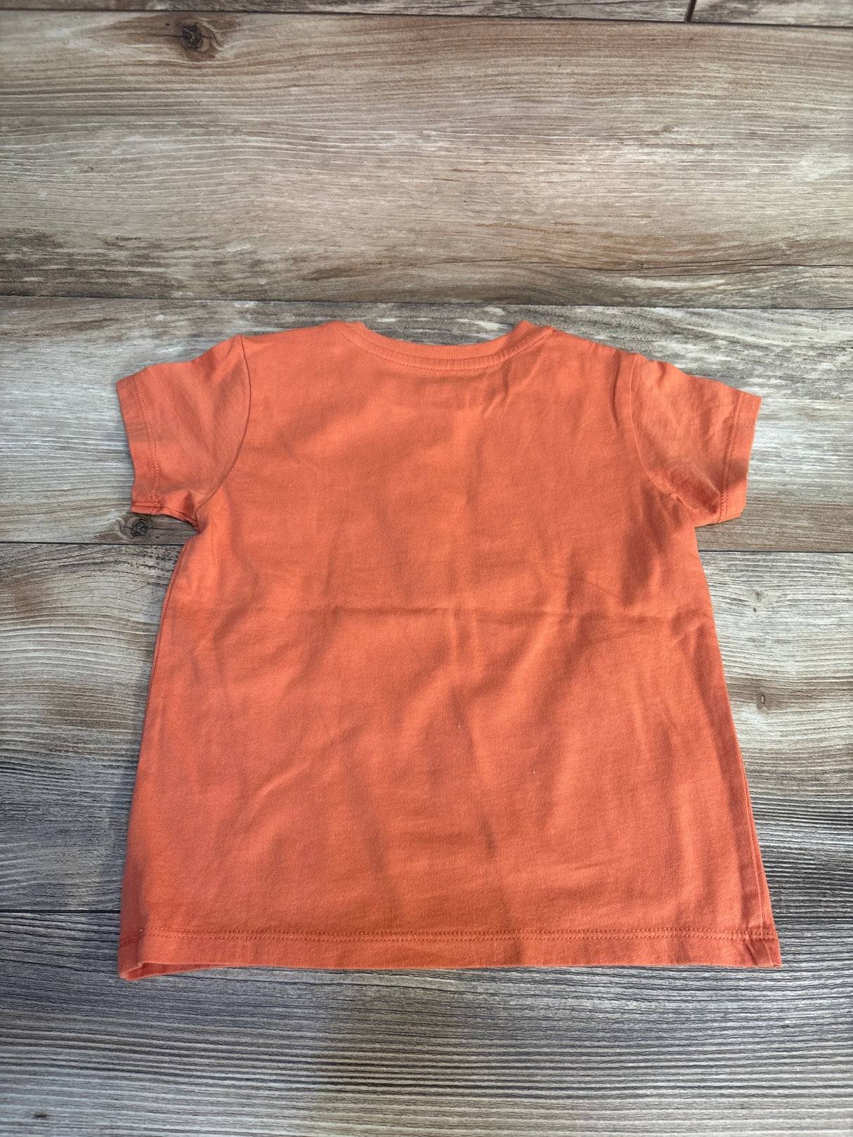 Orange kids short sleeve t-shirt on wood floor, resale clothing for children