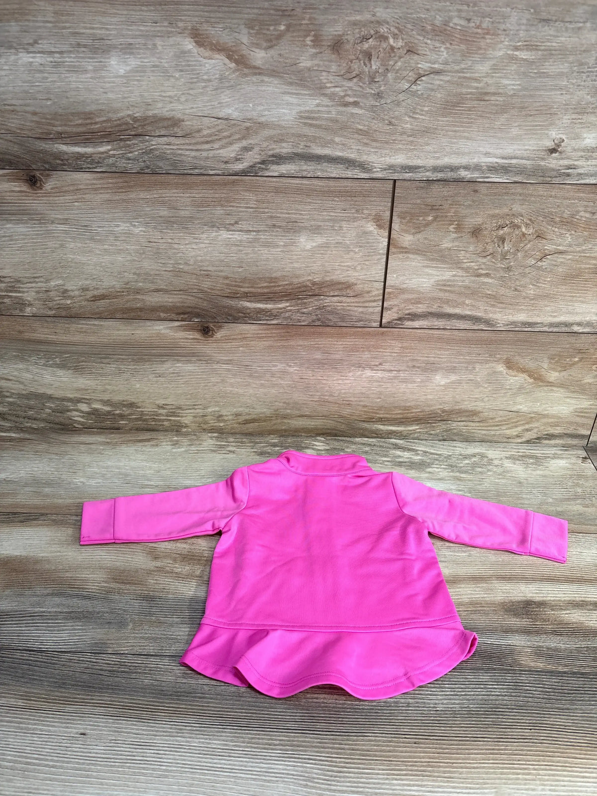 Back view of hot pink newborn Adidas full-zip track jacket showing long sleeves, ruffle hem and collar on wood background