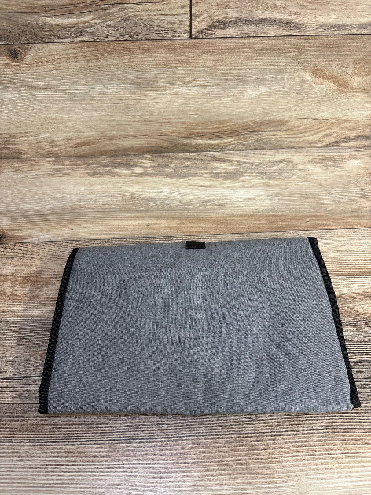 Gray fabric organizer pouch folded on wood floor, minimalist home accessory