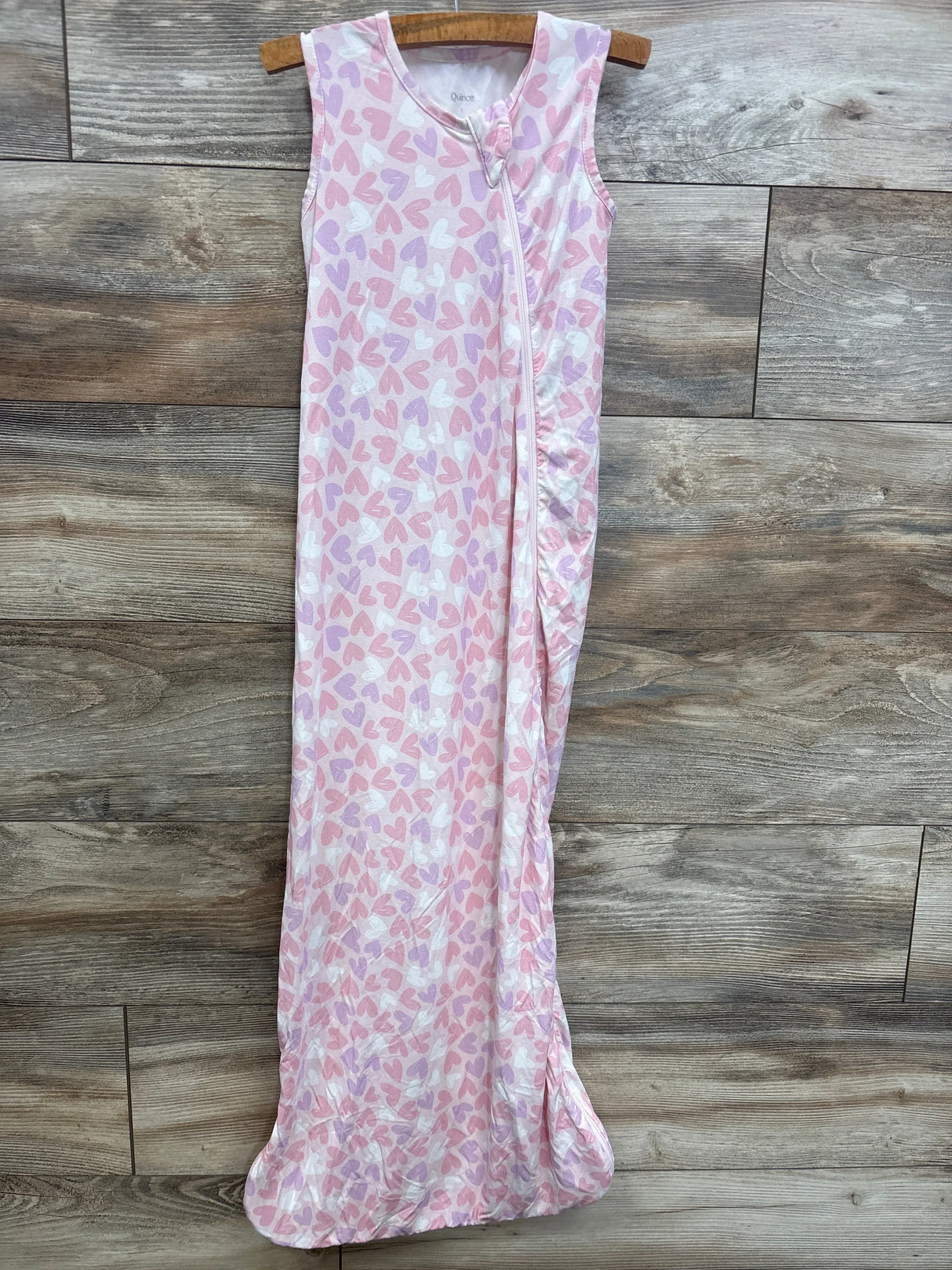 Pink and white sleeveless baby sleep sack with heart print, zip front, hanging on wood