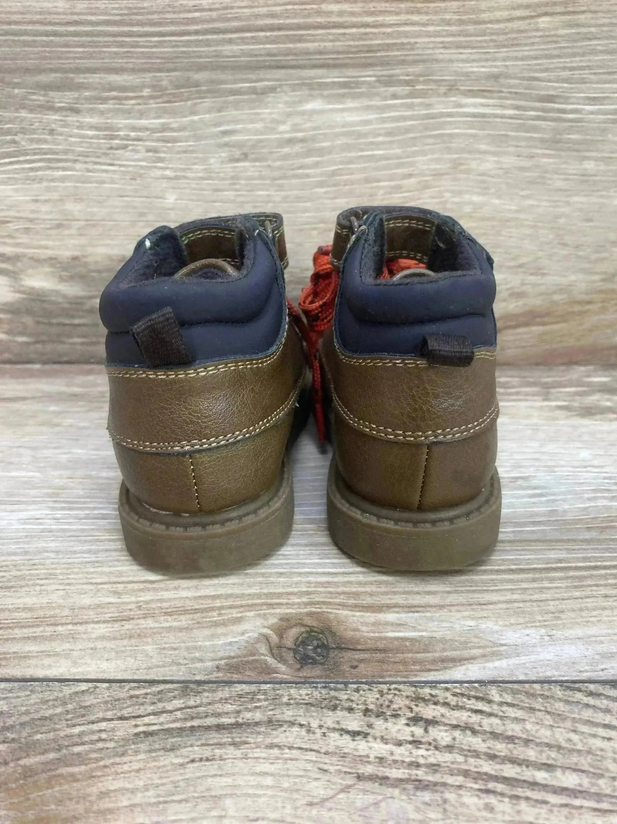 Back view of Carter’s Norman ankle boots showcasing brown faux leather, padded navy collar and red laces on wood background