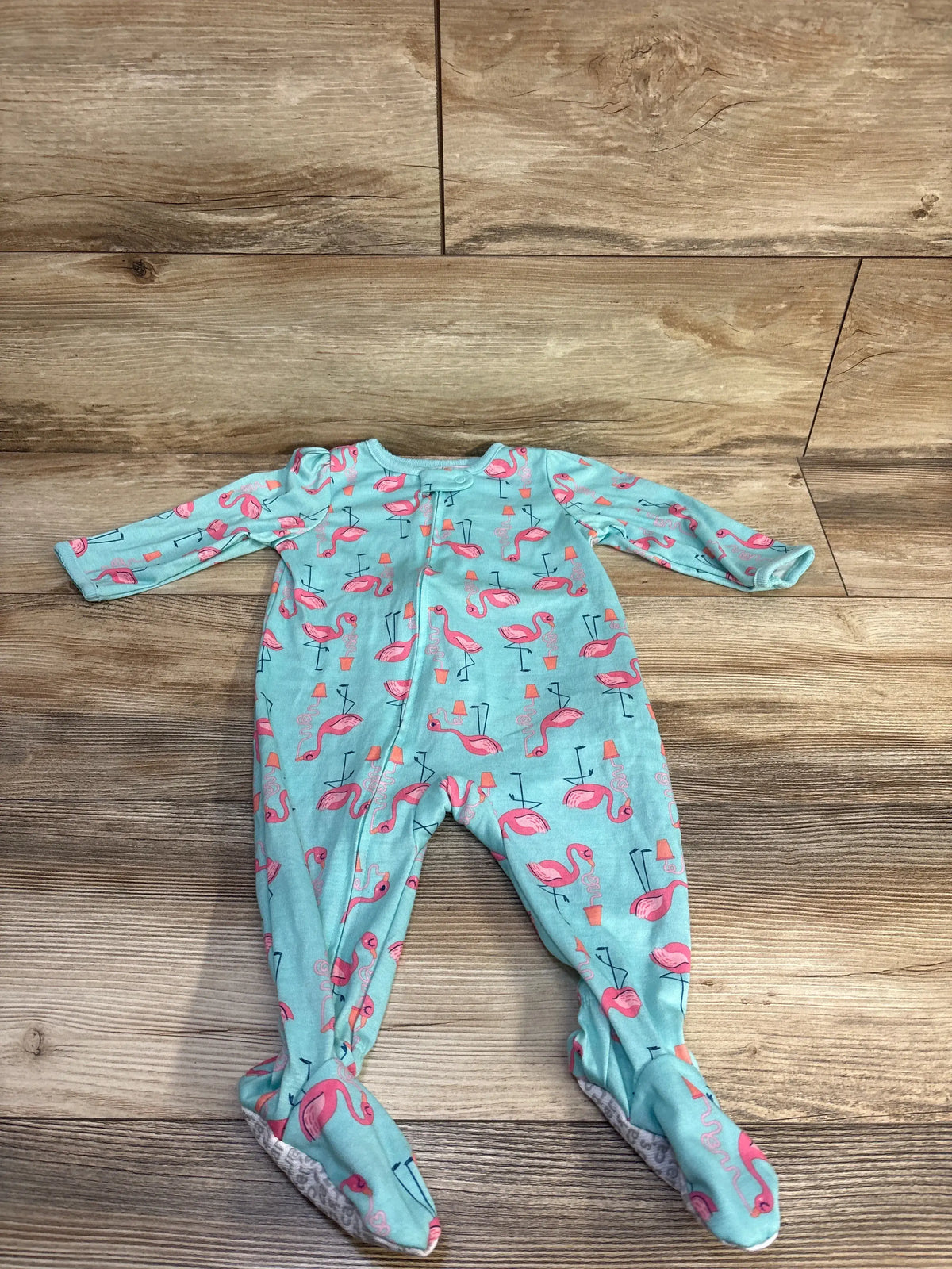 Front view of Simple Joys blue flamingo print sleeper with long sleeves, footed legs, and full zipper on wood background