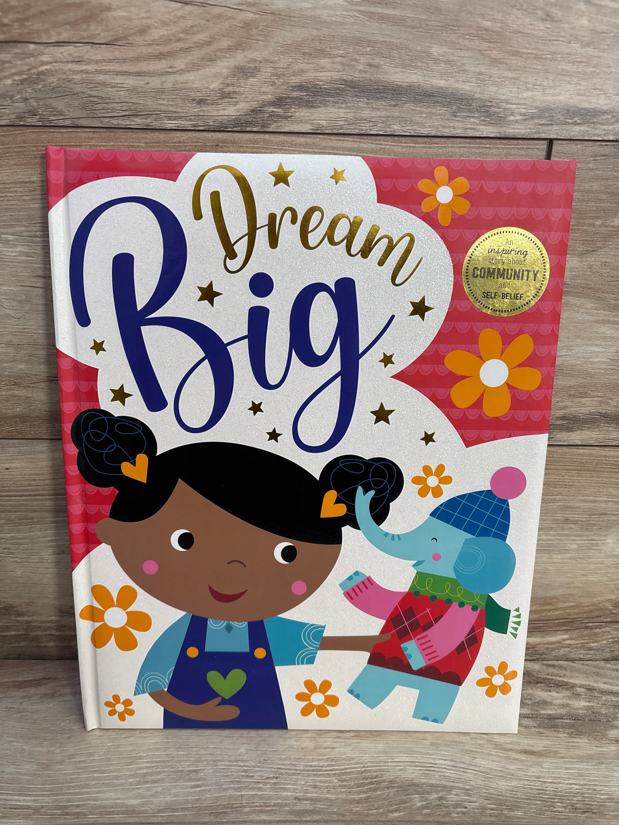 Children's book cover titled Dream Big with cartoon girl holding a toy elephant, colorful flowers