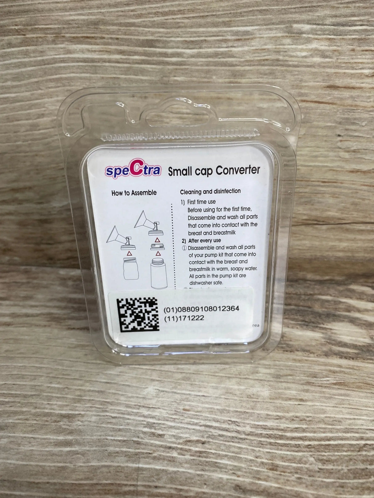 Front view of Spectra small-to-wide neck cap adapter packaging showing instruction card and QR code on wood surface