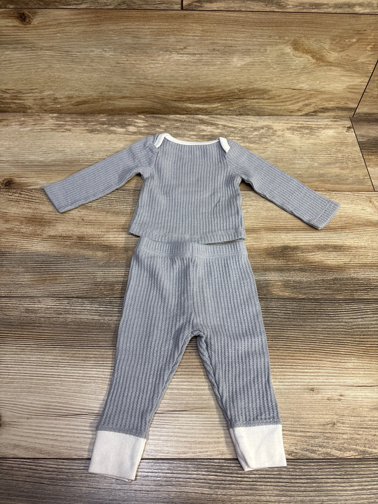 Top-down view of Cloud Island grey textured newborn shirt and pants set with white cuffs and collar on a wooden background