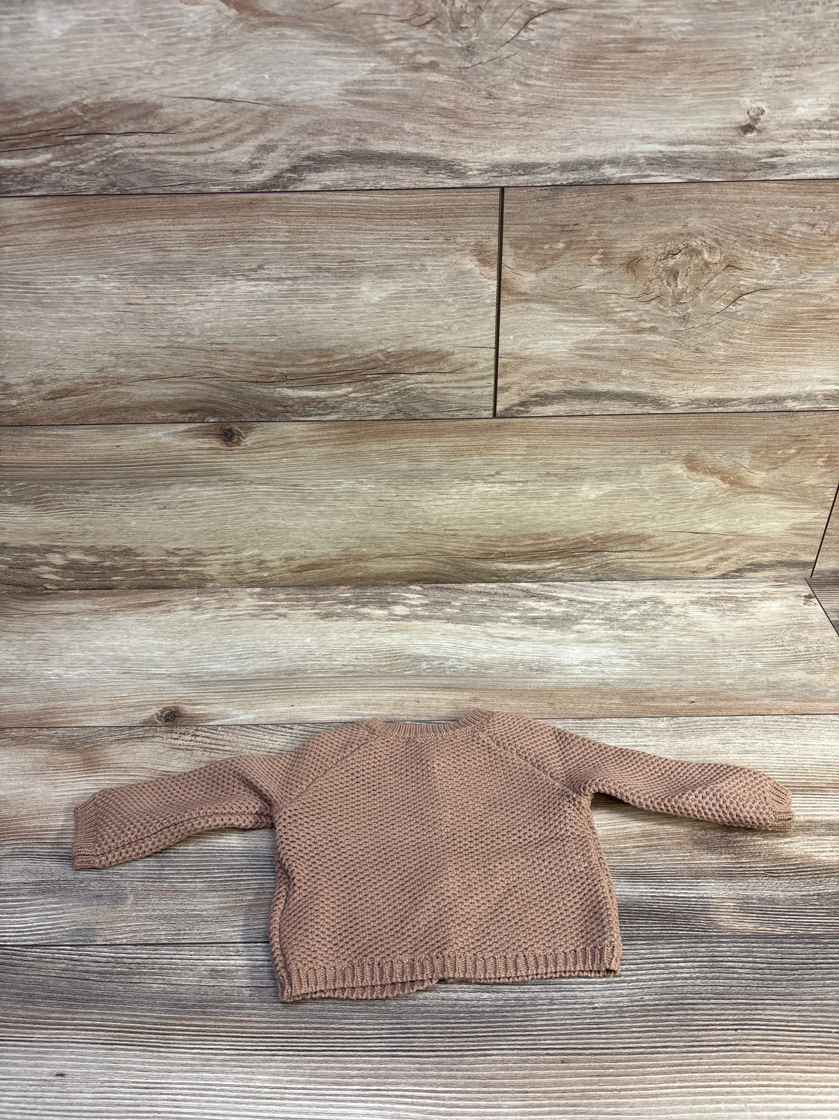 Flat lay of Cotton On Baby organic newborn knit cardigan showcasing seed-stitch texture and raglan sleeves on wood background