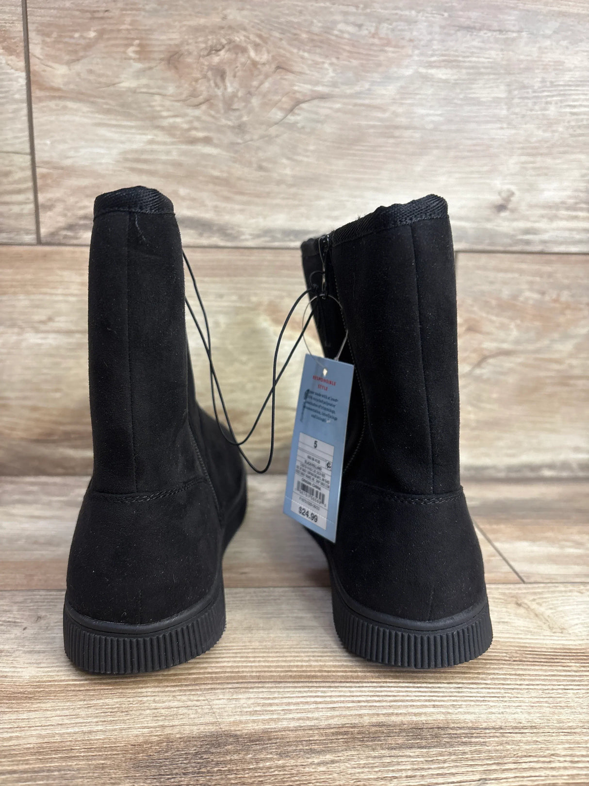 Back view of black children's suede boots with tag on wooden floor