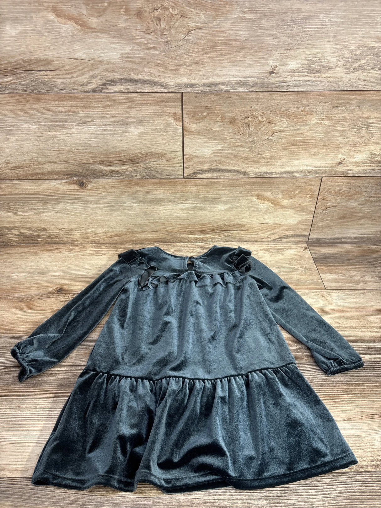 Black velvet long sleeve toddler dress with ruffle details on wooden background