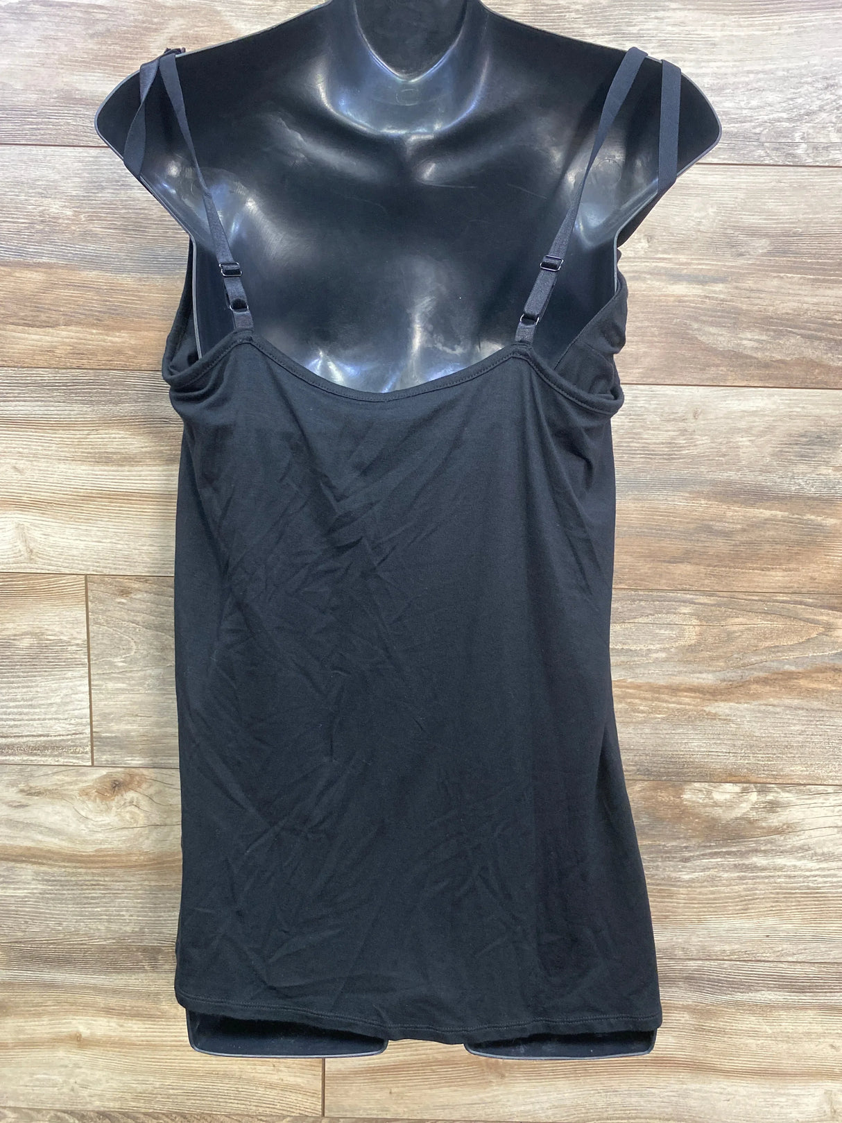Black camisole tank top with adjustable straps on mannequin, wood background
