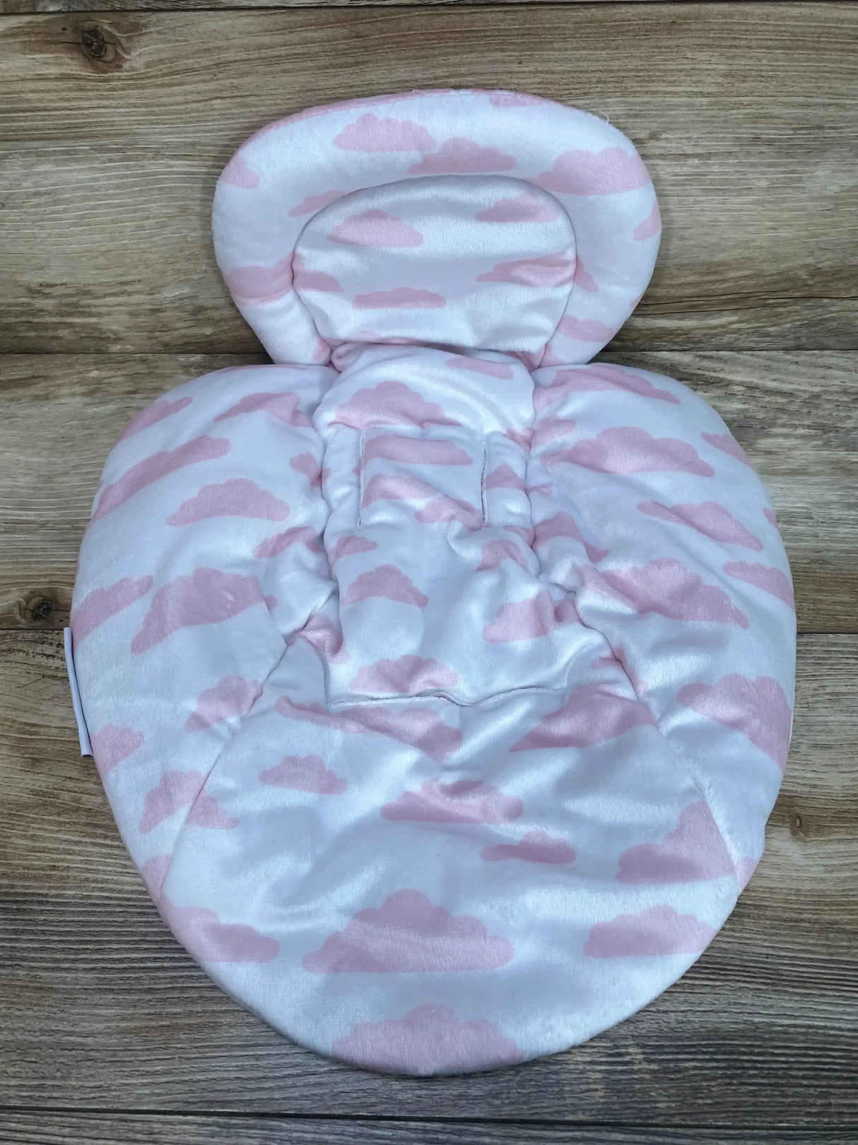 Overhead view of reversible swing insert in pink cloud print showing padded headrest, contoured body support and harness slots on wood background